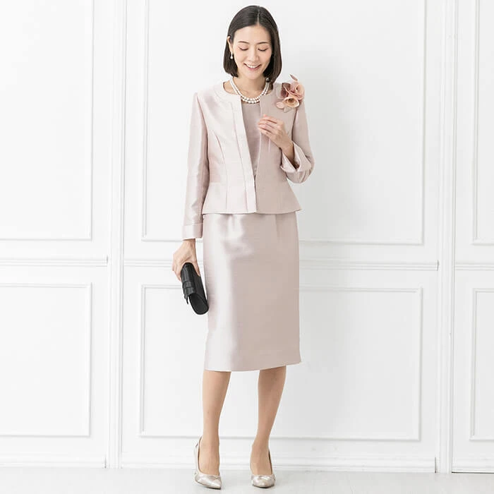 Pale pink coat and skirt outfit with low-heeled pumps and a small structured clutch