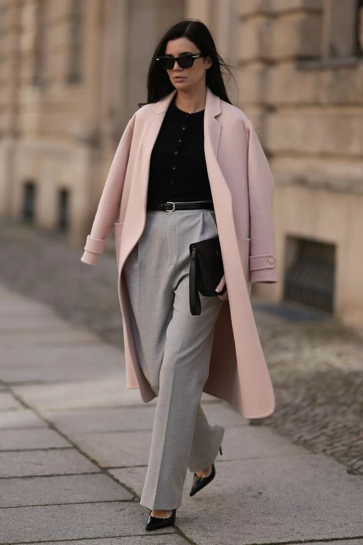 Soft pink wrap coat outfit with straight-leg trousers, black pointed heels and a chic crossbody bag