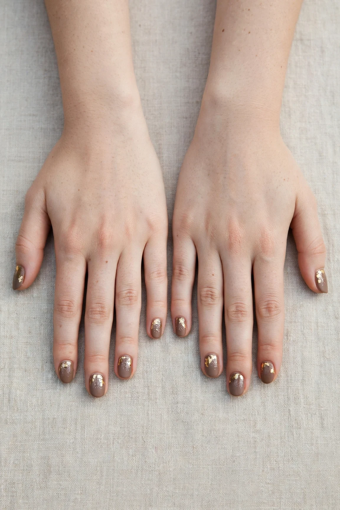 Short Oval Brown Neutral Matte Christmas Nails with a glitter gradient finish and gold foil accents