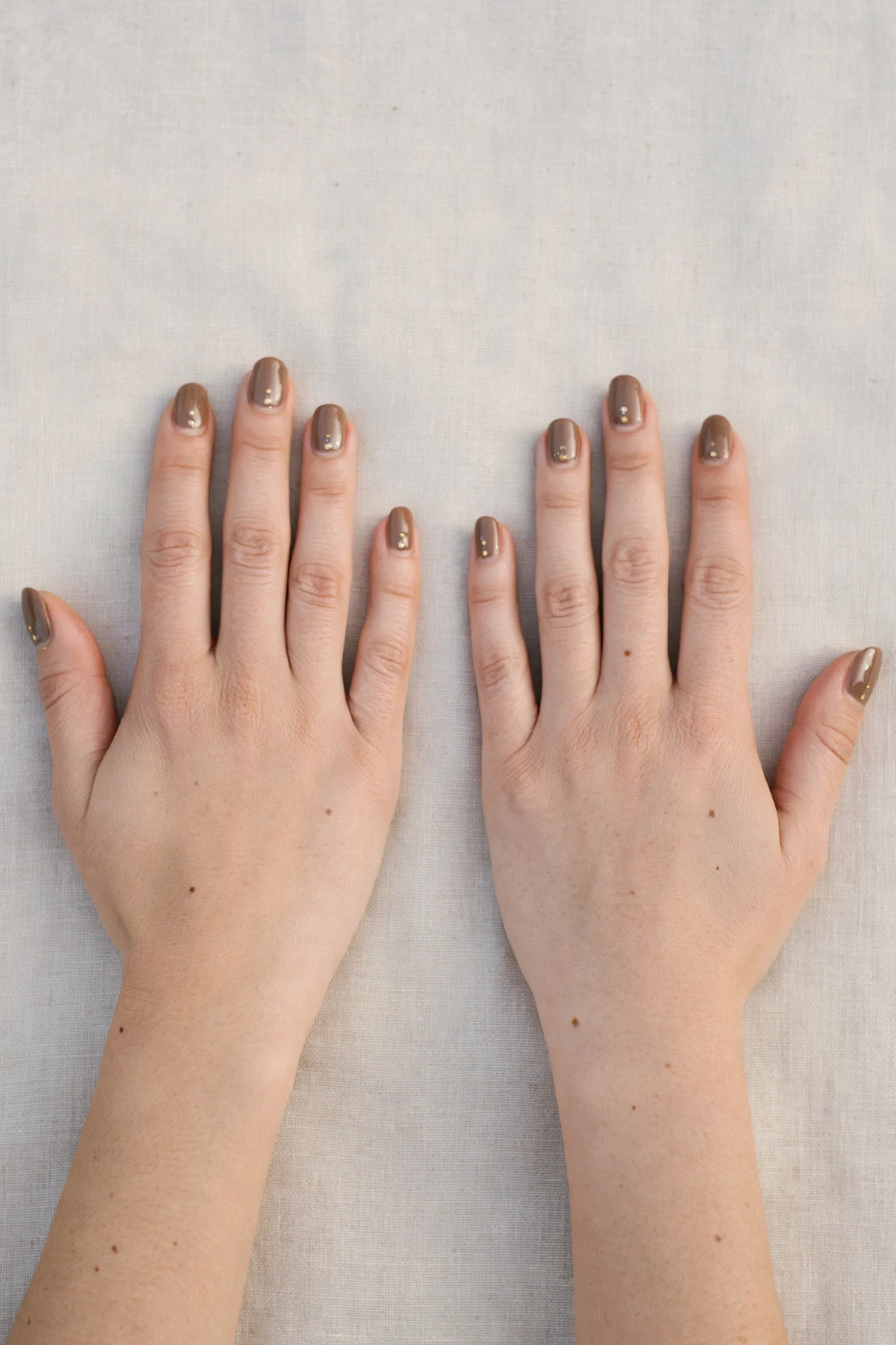Short Oval Brown Neutral Matte Christmas Nails with a high-gloss finish and tiny gold dots