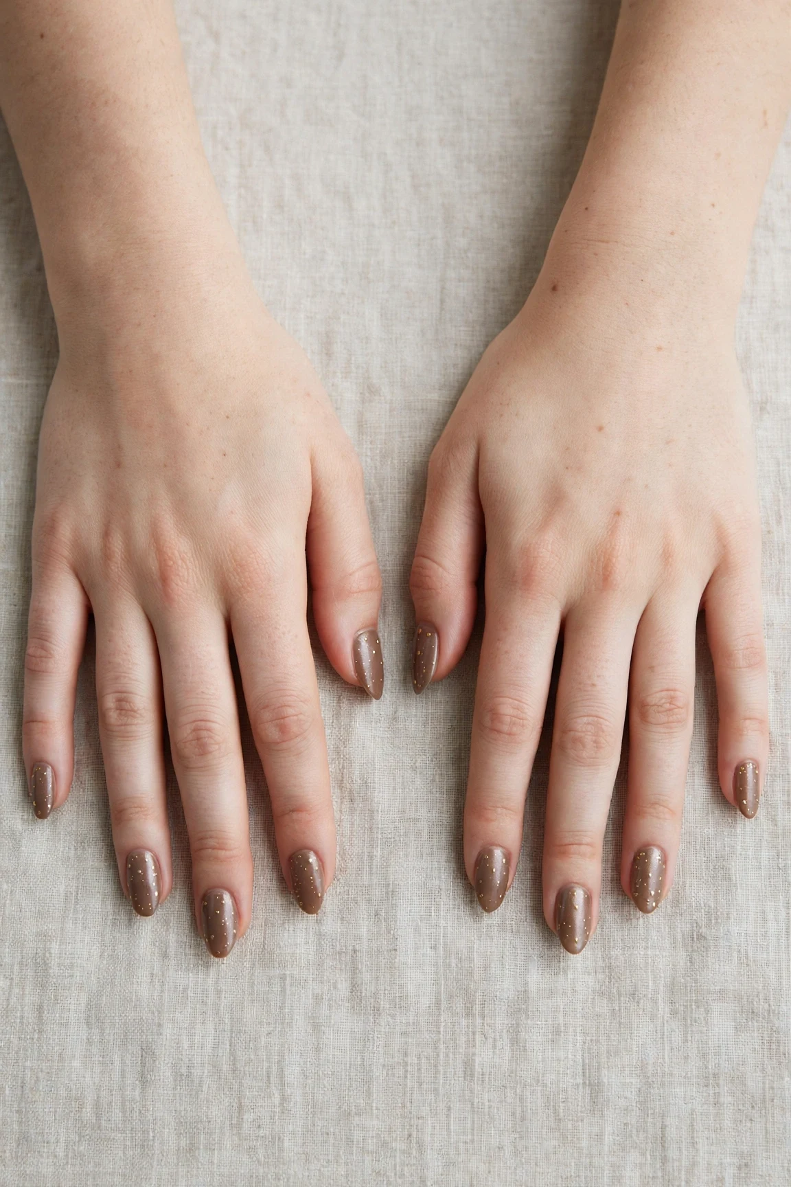 Almond Brown Neutral Matte Christmas Nails with a pearl shimmer finish and tiny gold dots