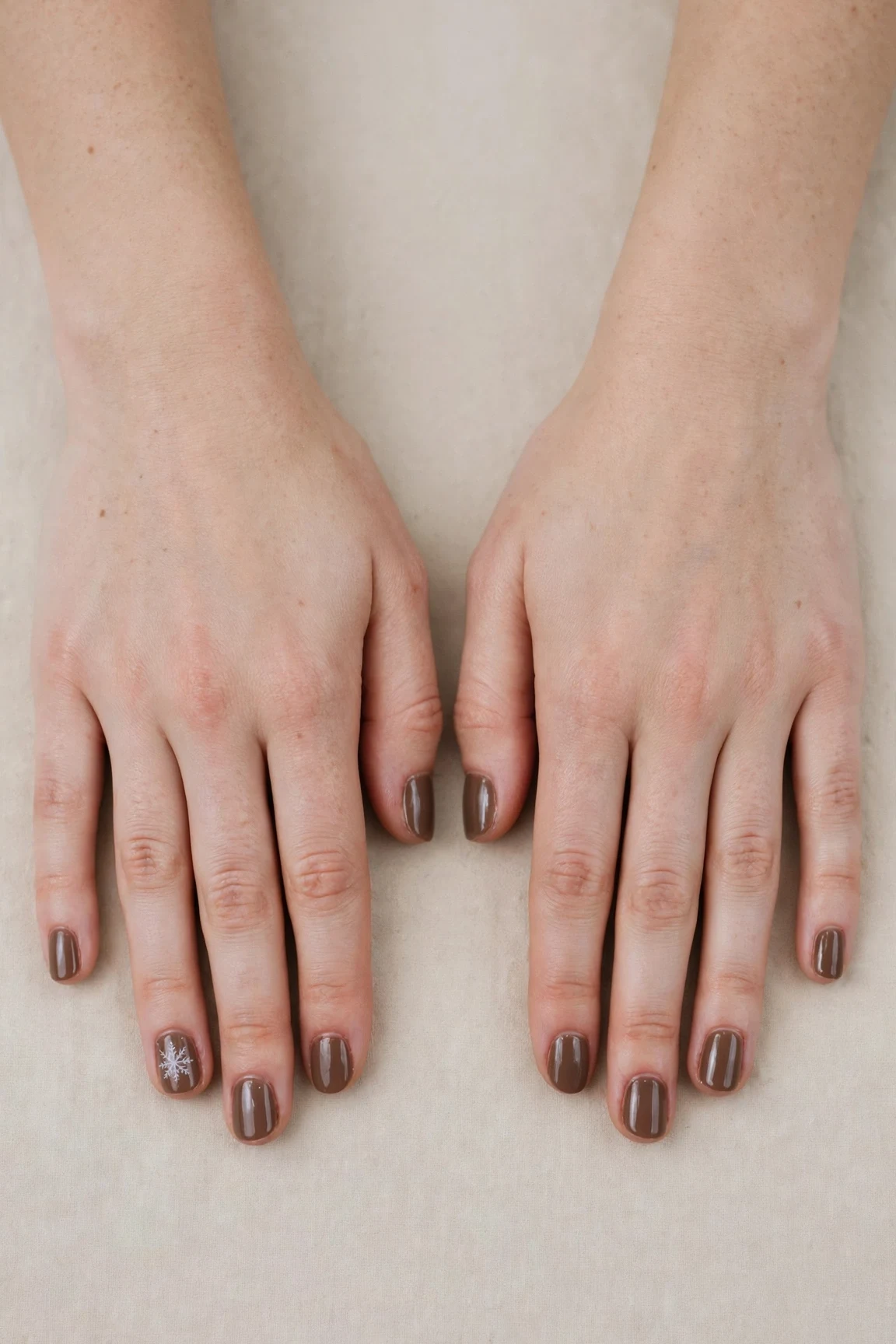Short Round Brown Neutral Matte Christmas Nails with a deep glossy shine and a delicate snowflake on the ring finger