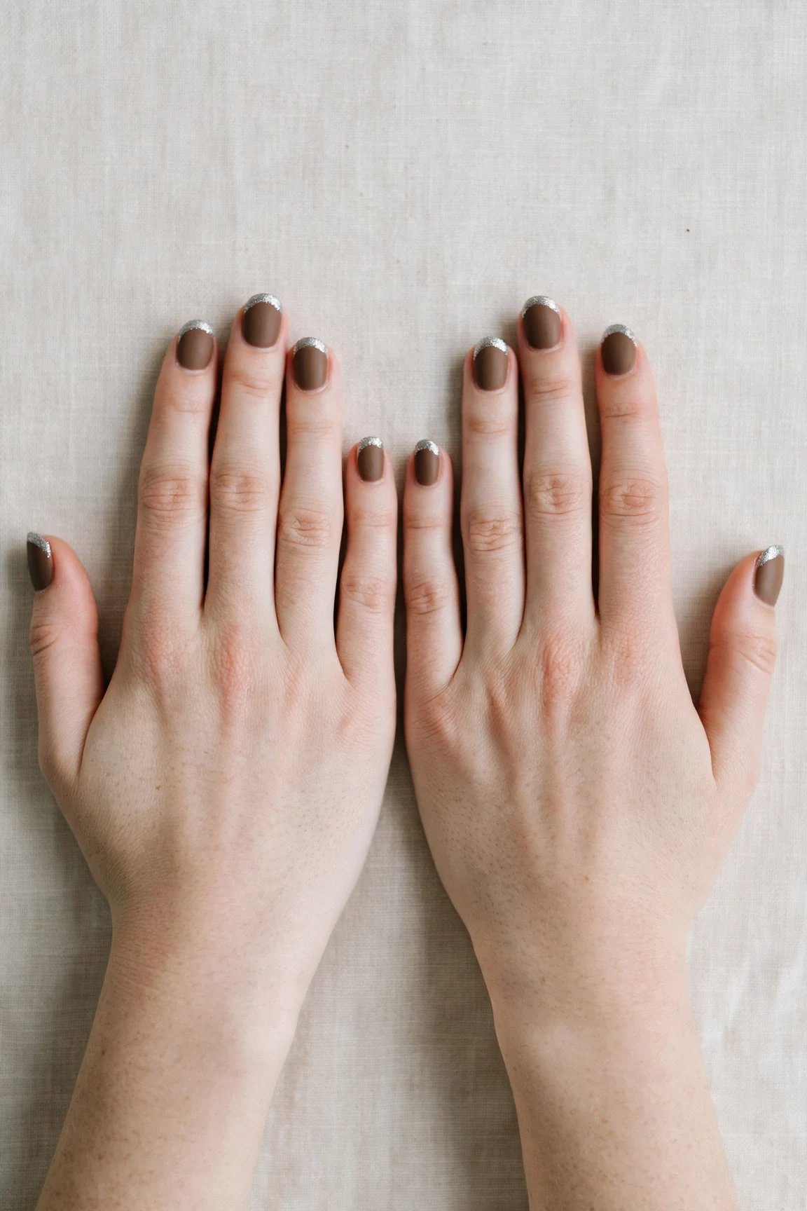 Oval Brown Neutral Matte Christmas Nails with a velvet matte finish and silver shimmer tips