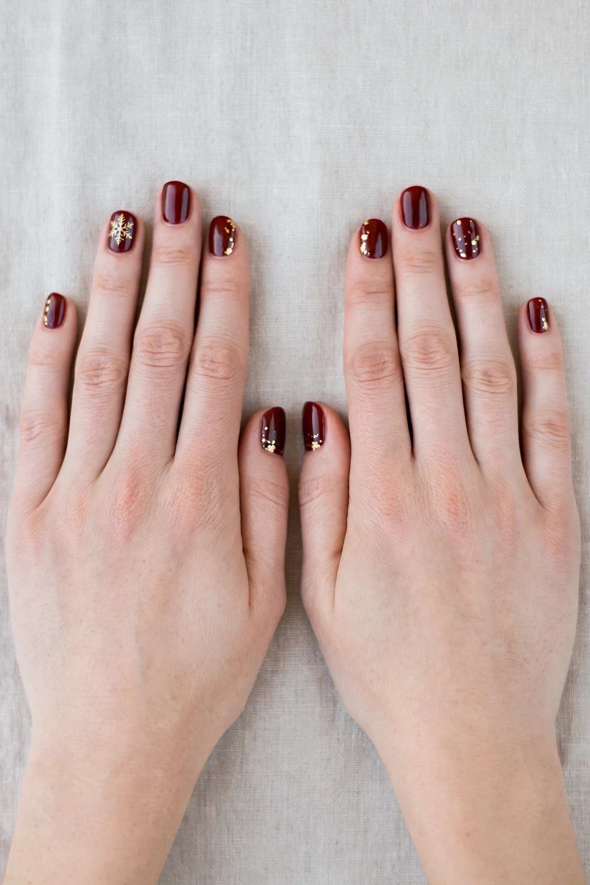 25 Cherry Cola Nail Designs With Gold Accents For Winter Weddings That Are Chic, Warm and Elegant 26 Short Oval Cherry Cola Nail Designs with Gold Accents with a high-gloss finish and a delicate snowflake on the ring finger