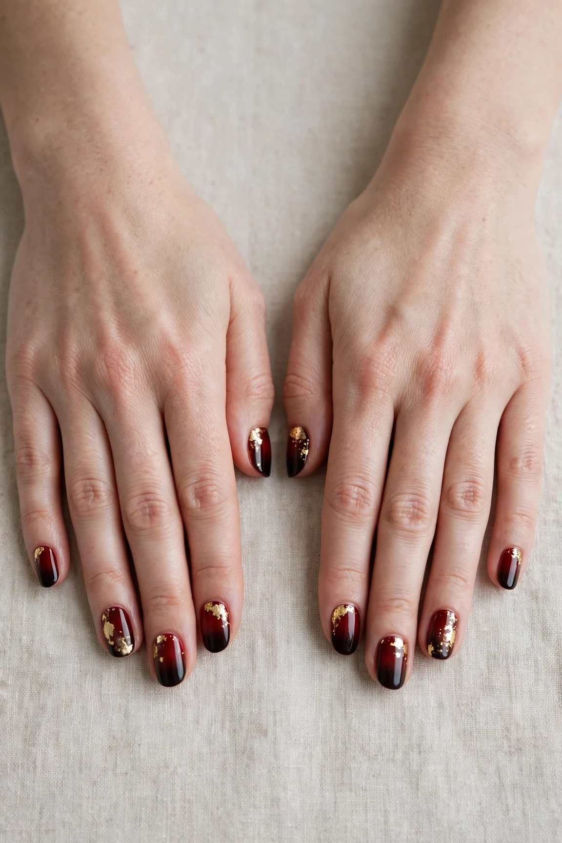 Short Oval Cherry Cola Ombre Nails with a high-gloss finish and gold foil accents
