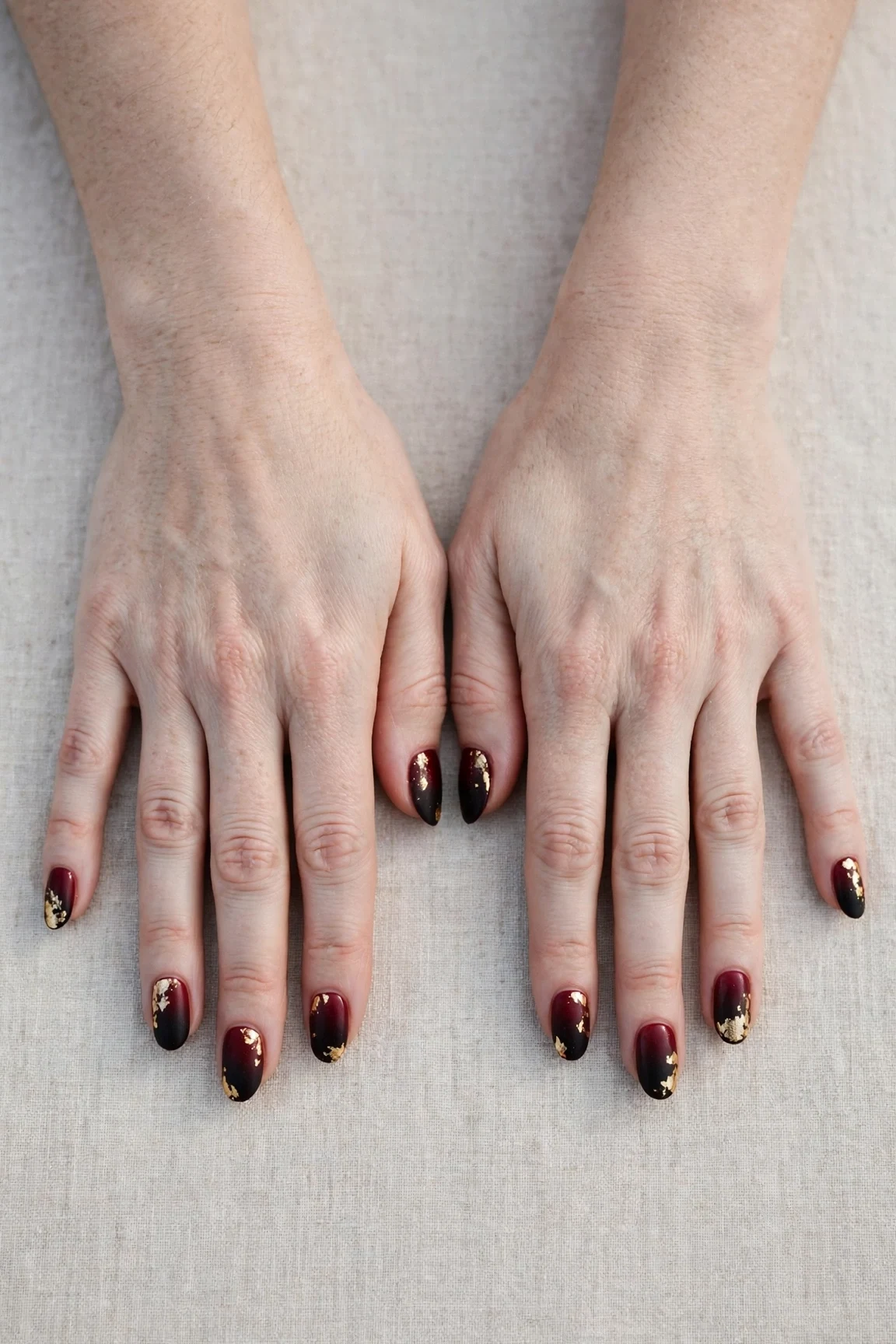 Oval Cherry Cola Ombre Nails with a velvet matte finish and gold foil accents