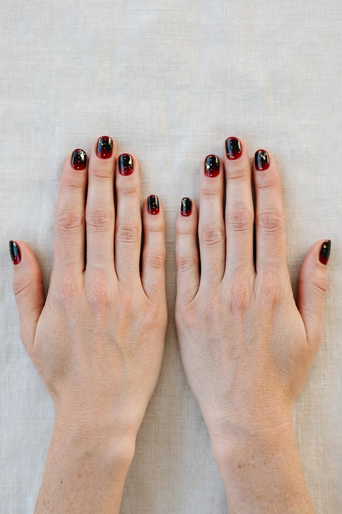 Short Oval Cherry Cola Ombre Nails with a high-gloss finish and tiny gold dots
