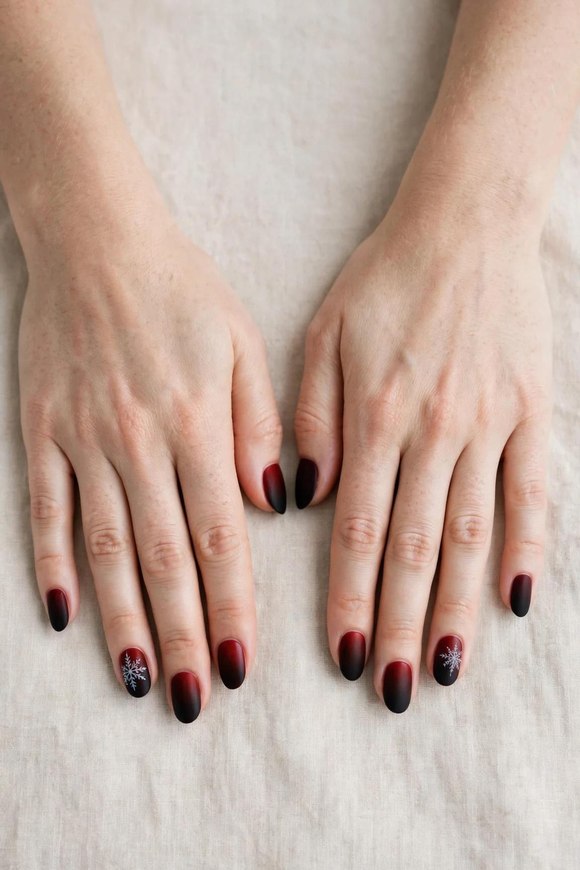 Oval Cherry Cola Ombre Nails with a velvet matte finish and a delicate snowflake on the ring finger