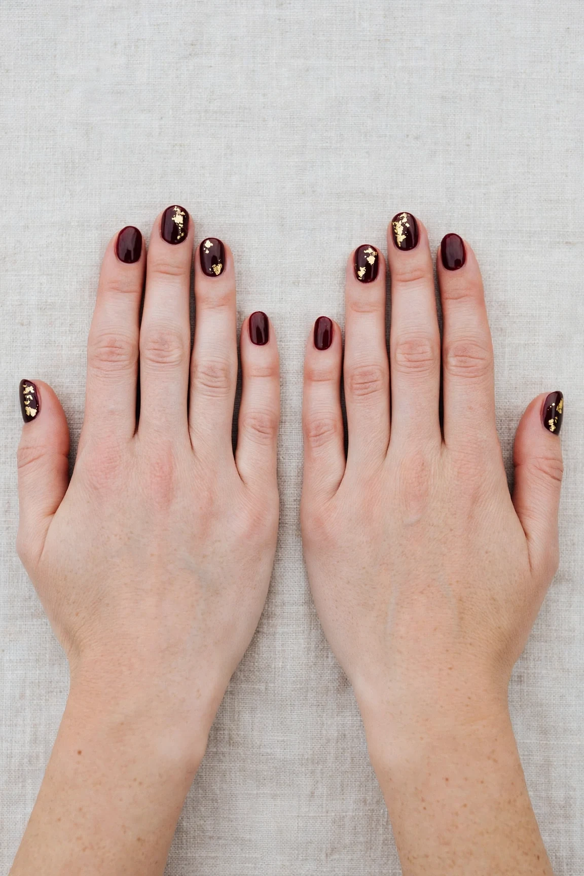 Short Oval Cherry Cola Velvet Finish Nails with a high-gloss finish and gold foil accents