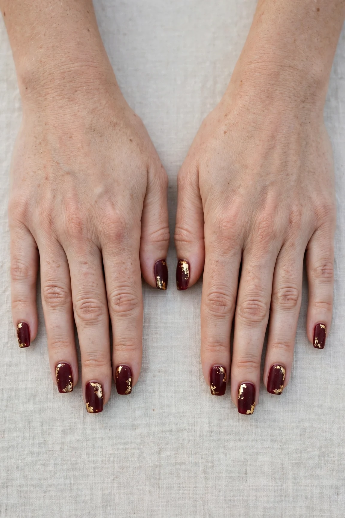 Squoval Cherry Cola Velvet Finish Nails with a creamy opaque finish and gold foil accents
