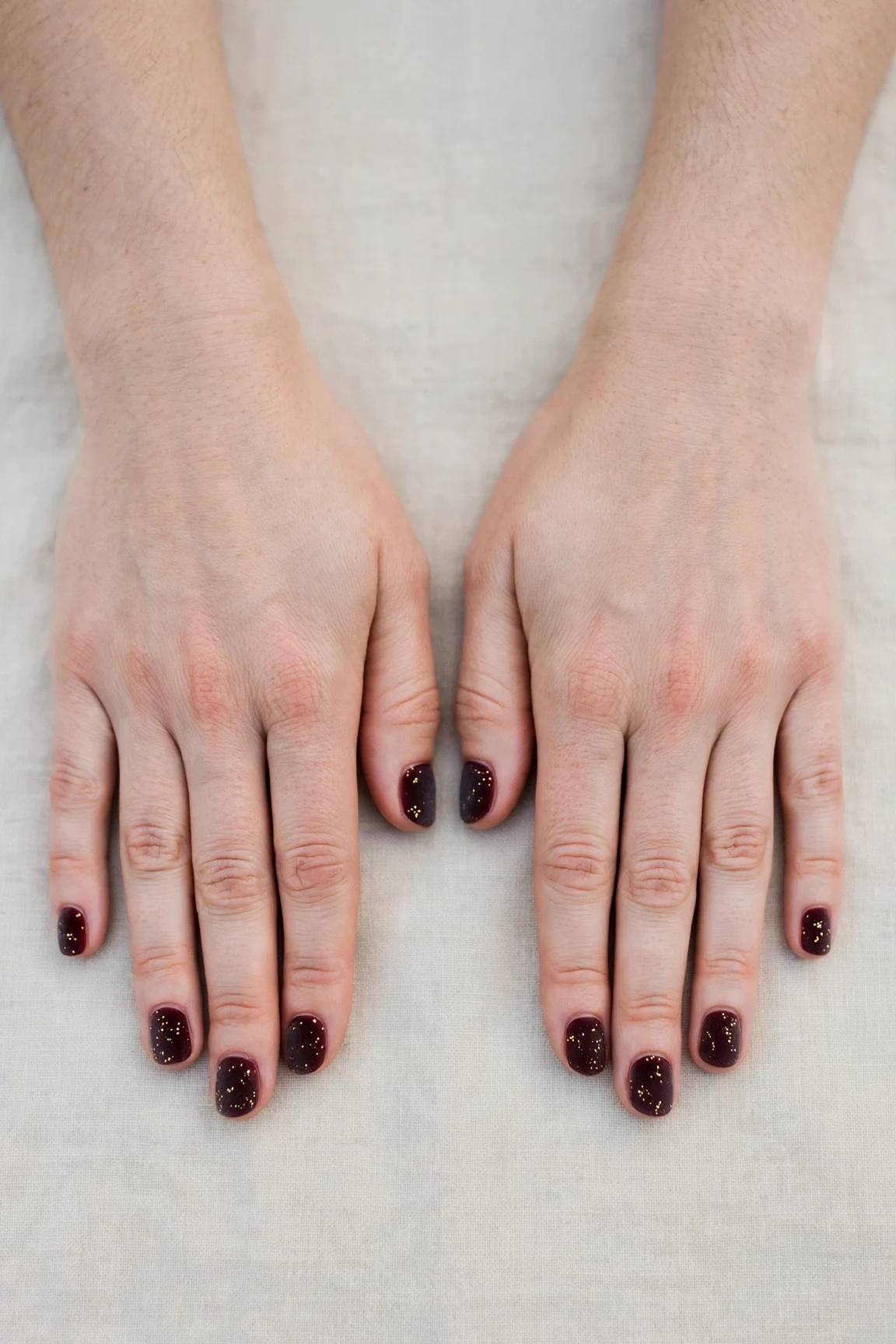 Short Round Cherry Cola Velvet Finish Nails with a frosted shimmer finish and tiny gold dots