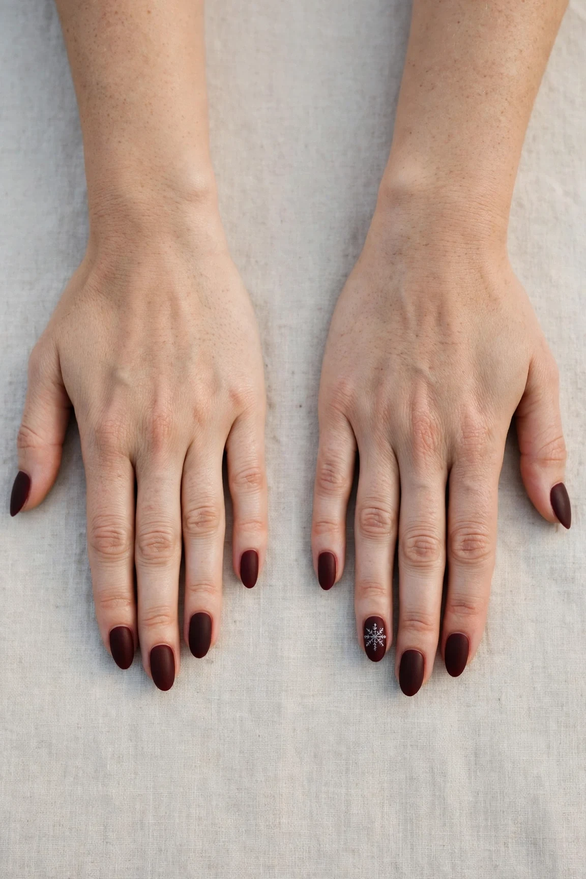 Almond Cherry Cola Velvet Finish Nails with a soft matte finish and a delicate snowflake on the ring finger