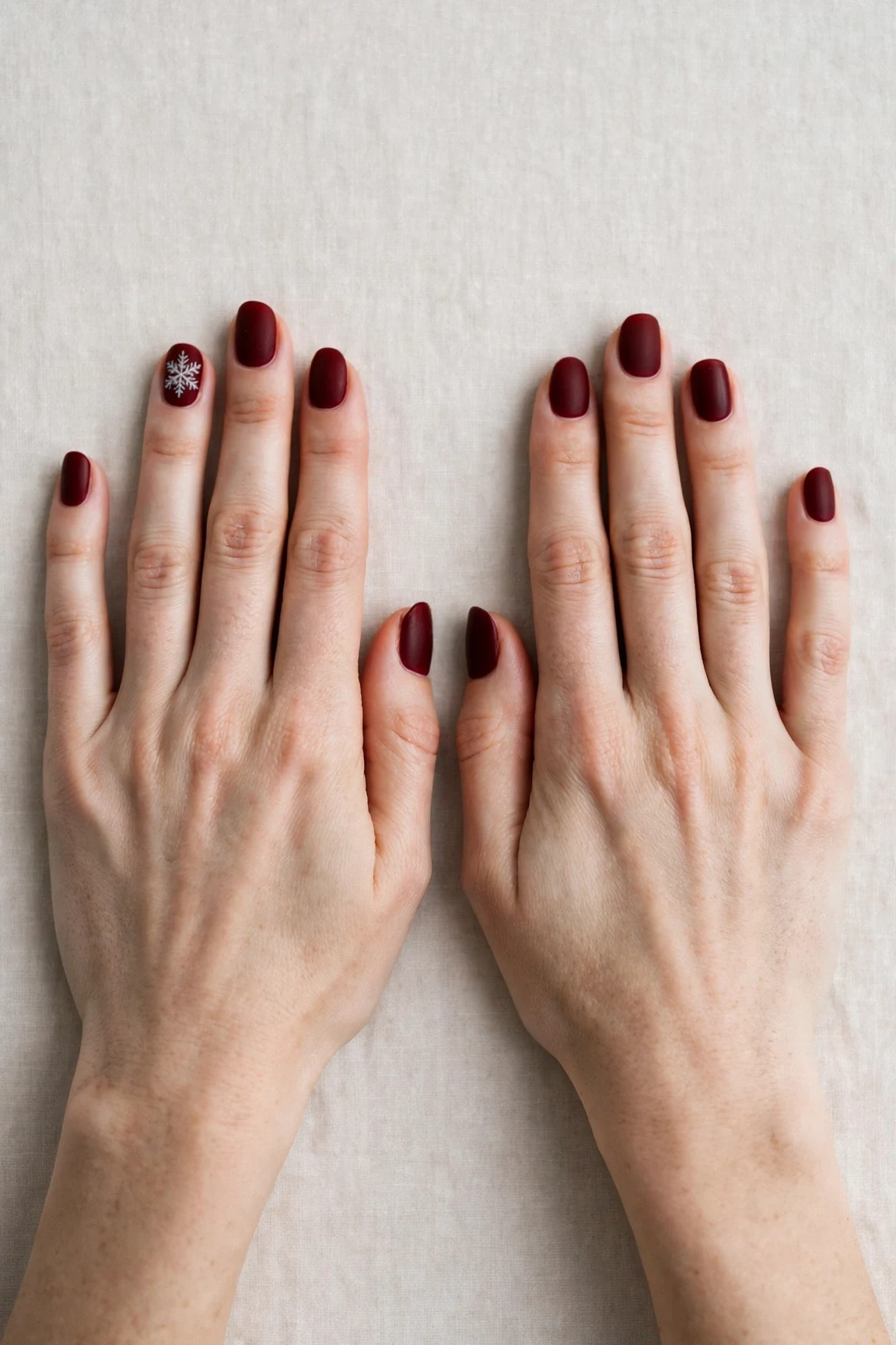 Oval Cherry Cola Velvet Finish Nails with a velvet matte finish and a delicate snowflake on the ring finger