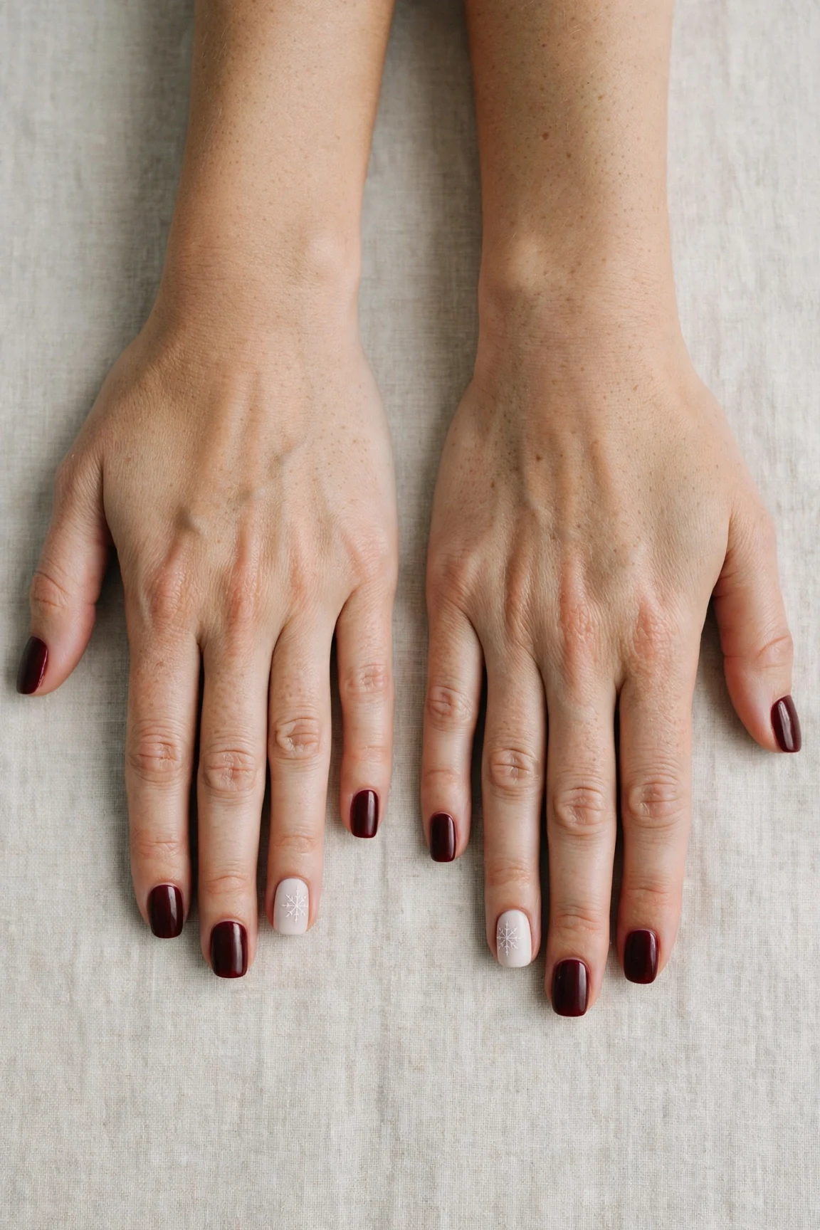 Squoval Cherry Cola Velvet Finish Nails with a creamy opaque finish and a delicate snowflake on the ring finger