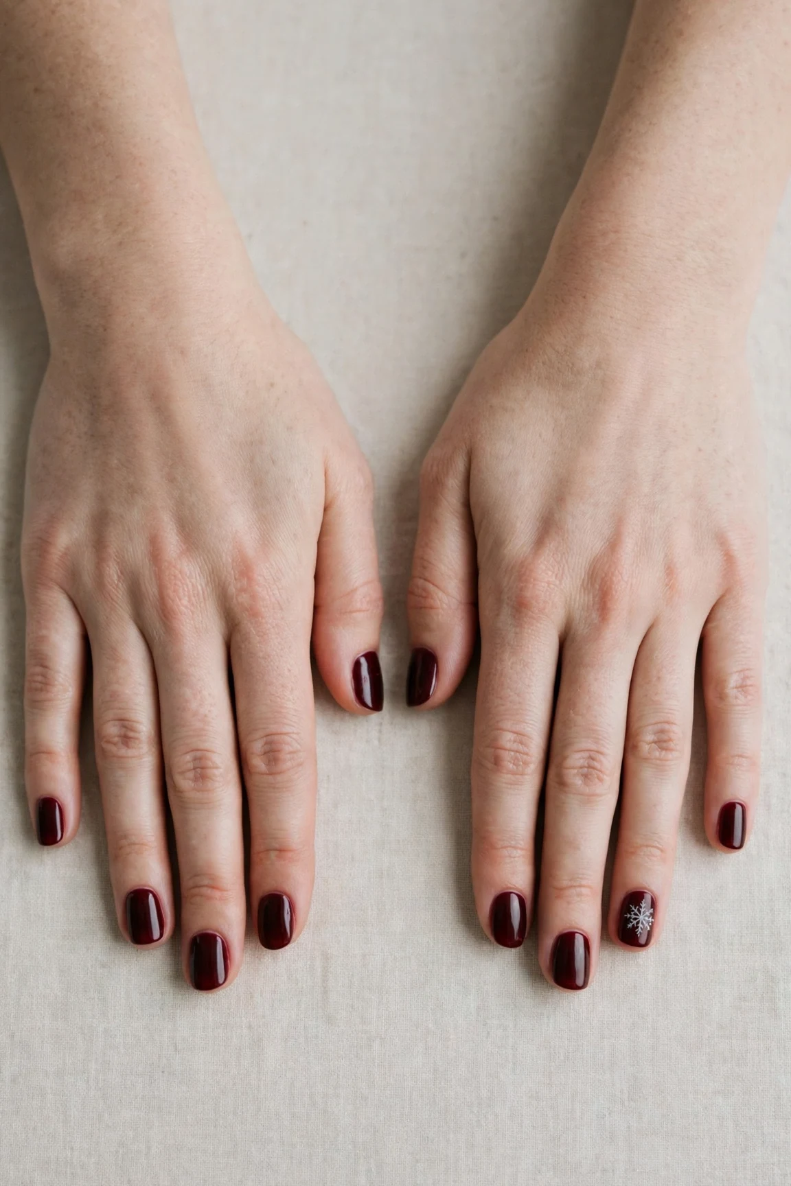 Short Round Cherry Cola Velvet Finish Nails with a deep glossy shine and a delicate snowflake on the ring finger