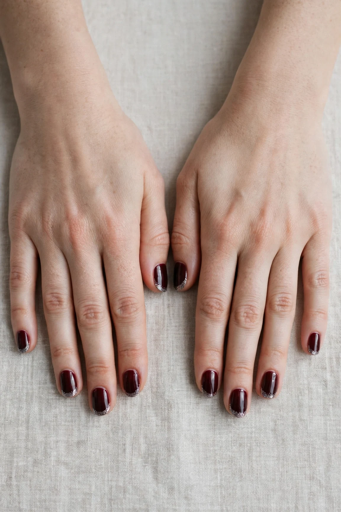 Short Oval Cherry Cola Velvet Finish Nails with a high-gloss finish and silver shimmer tips