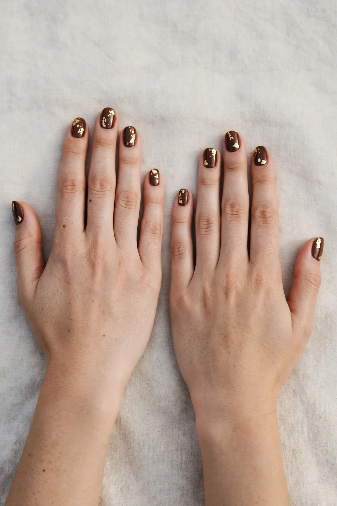 Short Oval Chocolate Brown Christmas Nail Art with a high-gloss finish and gold foil accents