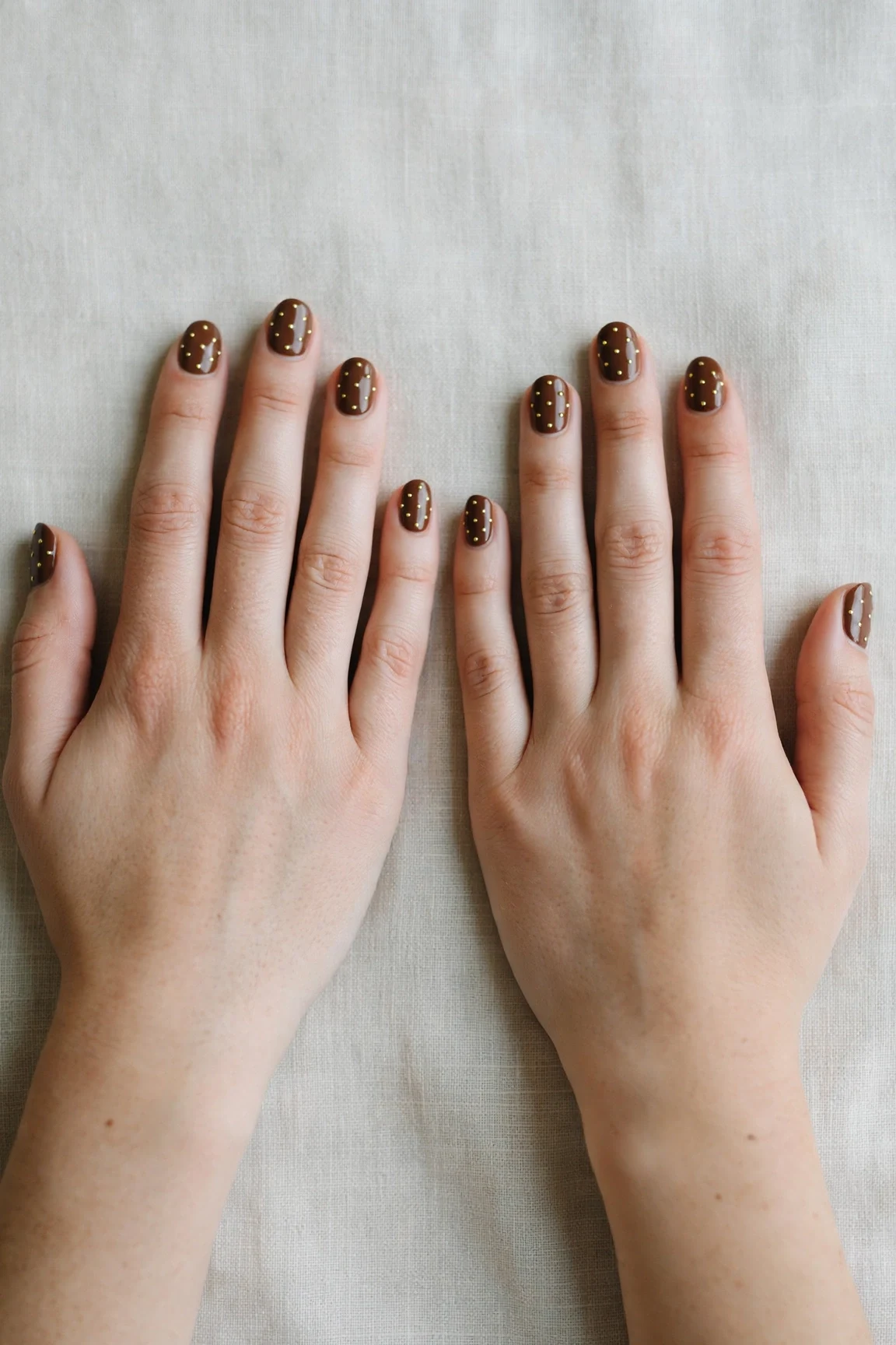 Short Oval Chocolate Brown Christmas Nail Art with a high-gloss finish and tiny gold dots