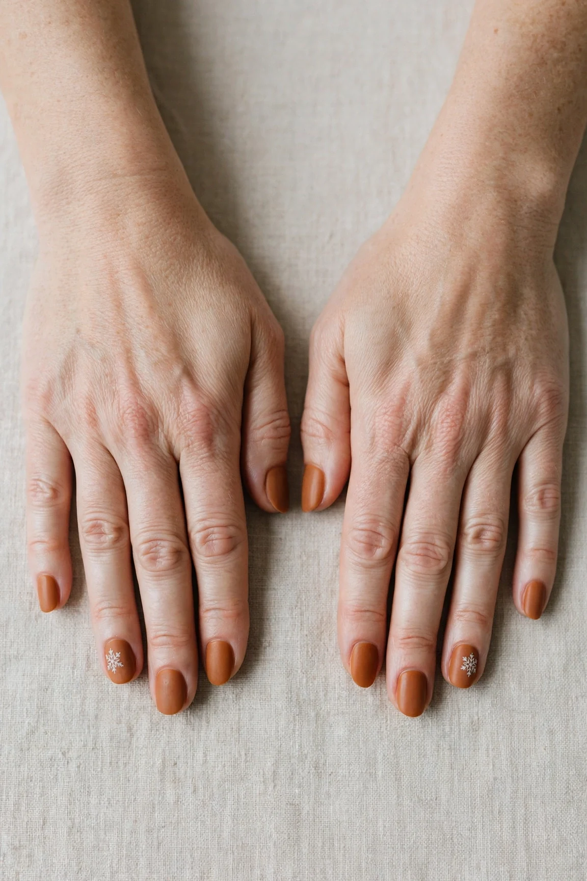 Oval Cinnamon Caramel Nail Art with a velvet matte finish and a delicate snowflake on the ring finger