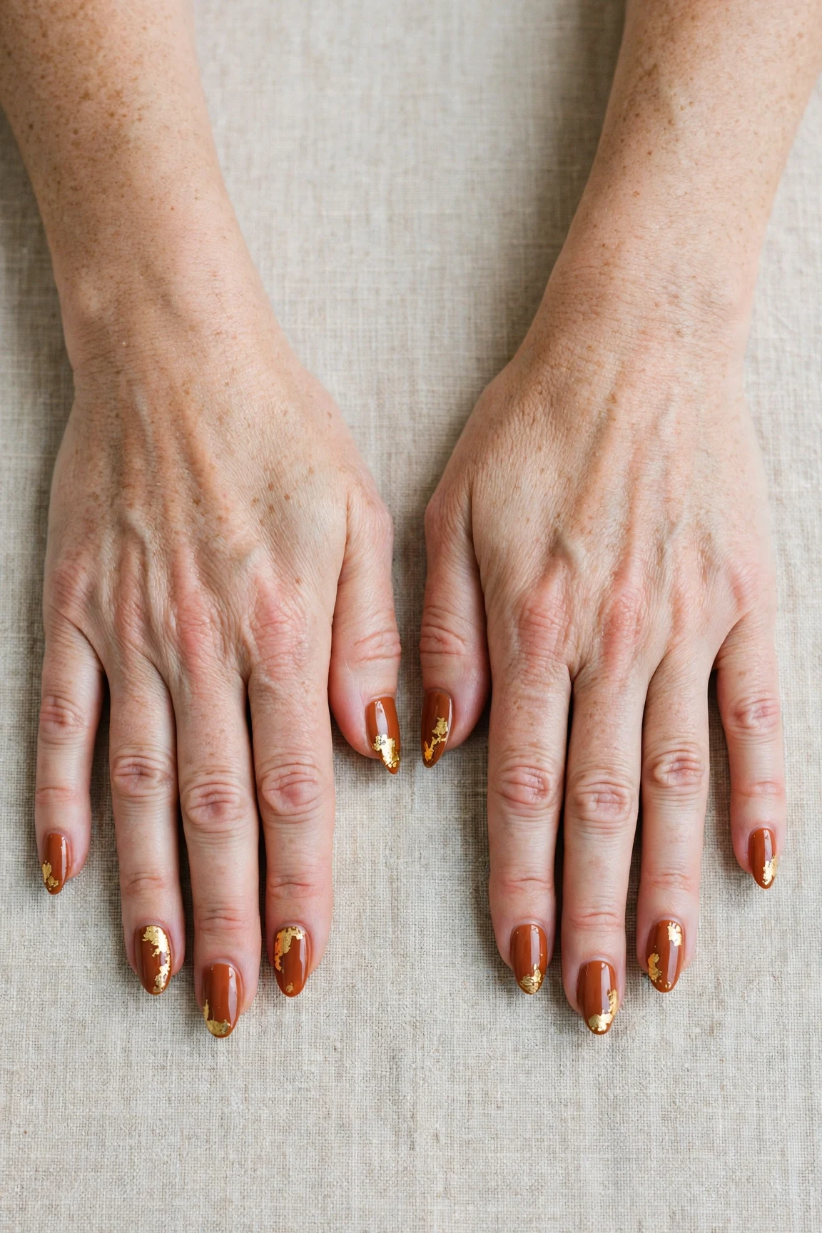 Cinnamon Spice Almond Nails with a high-gloss finish and gold foil accents