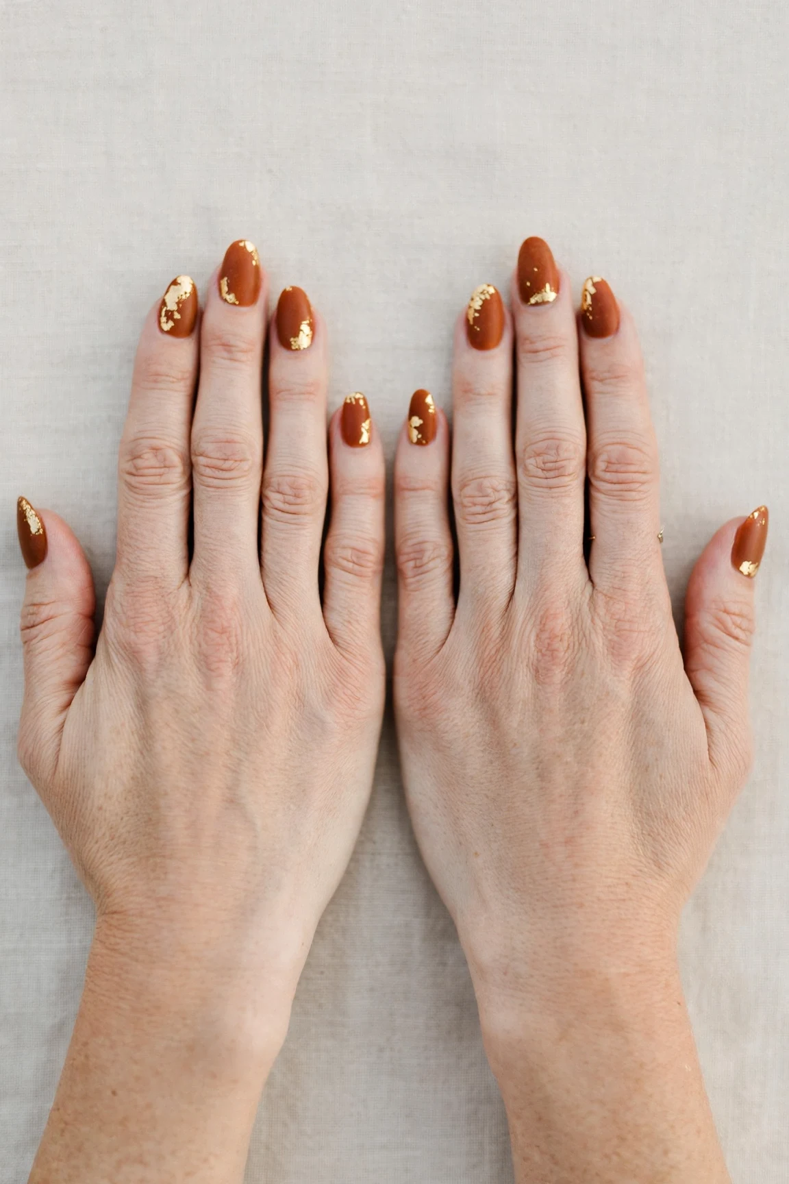 Cinnamon Spice Almond Nails with a velvet matte finish and gold foil accents