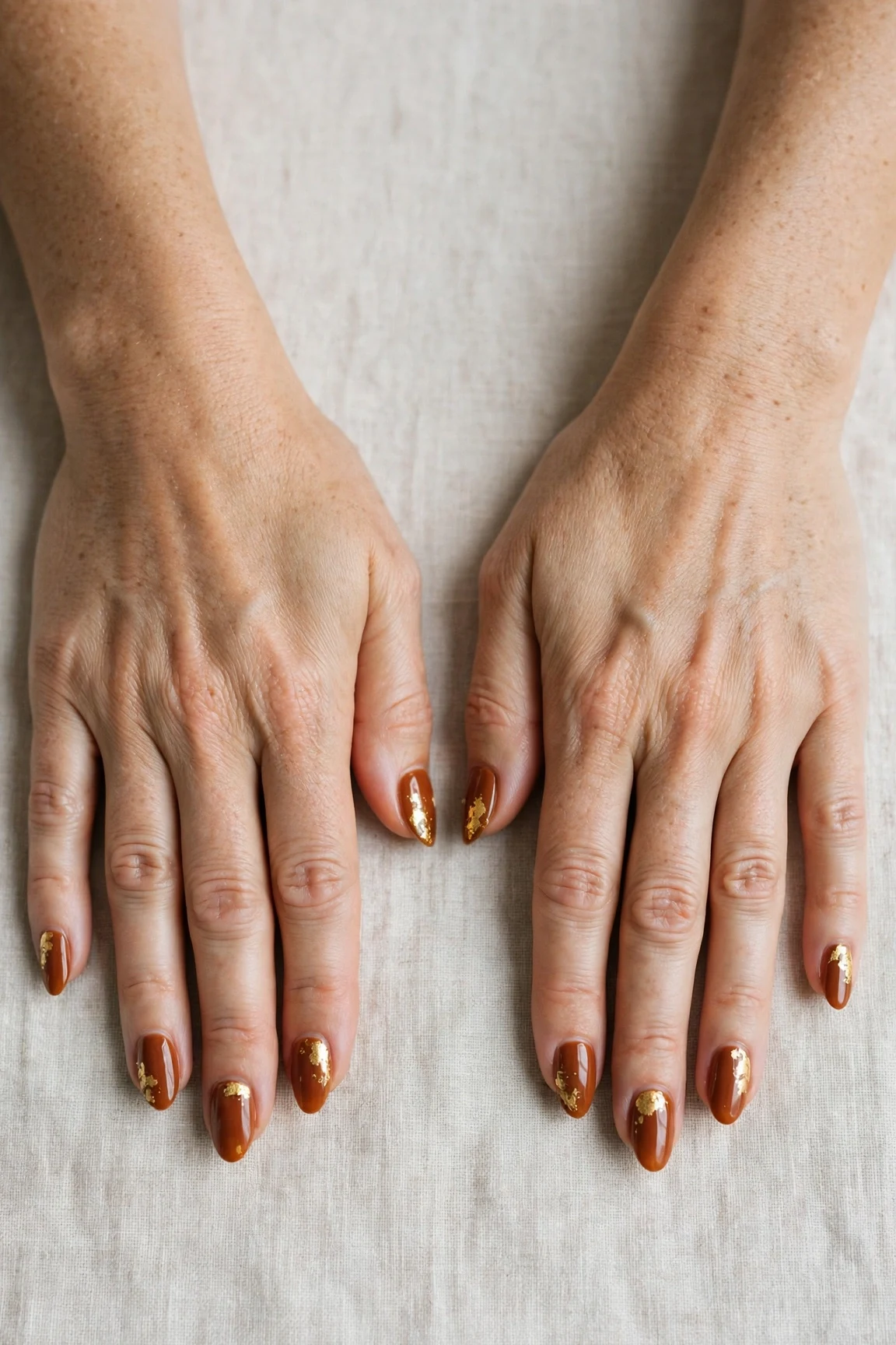 Cinnamon Spice Almond Nails with a deep glossy shine and gold foil accents