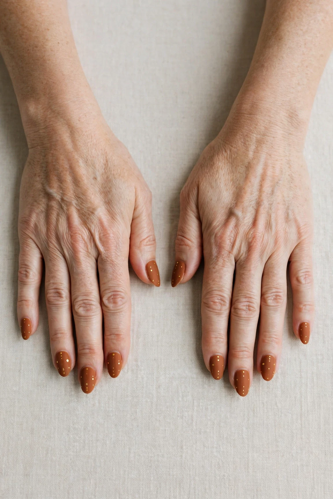 Cinnamon Spice Almond Nails with a velvet matte finish and tiny gold dots