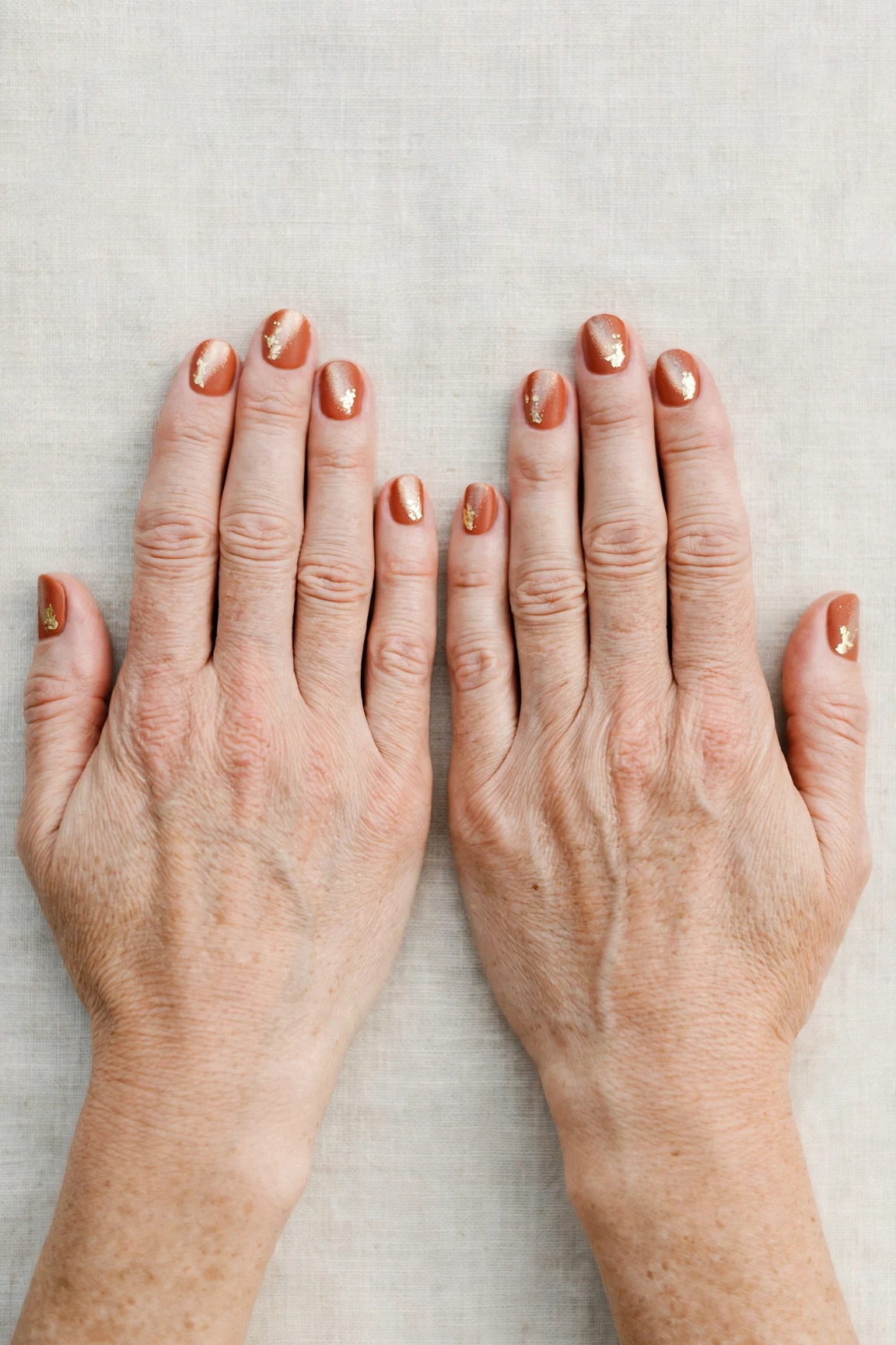 Cinnamon Terracotta Short Nails with a frosted shimmer finish and gold foil accents