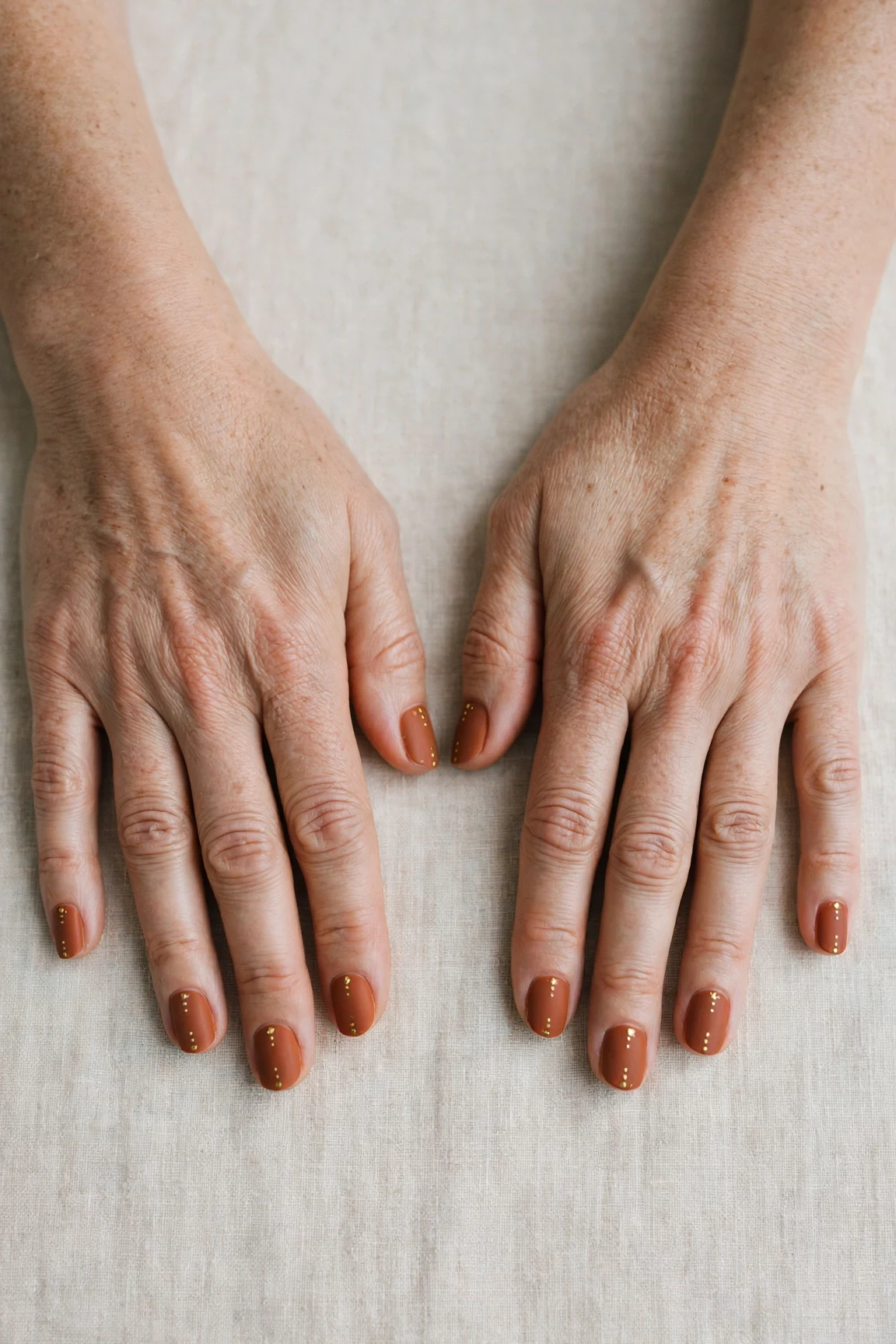 Cinnamon Terracotta Short Nails with a velvet matte finish and tiny gold dots