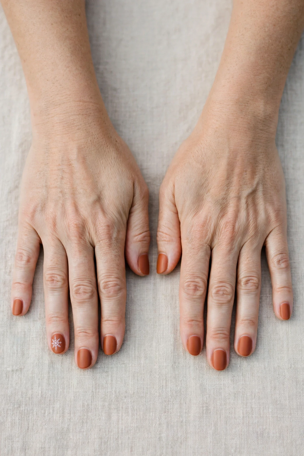 Cinnamon Terracotta Short Nails with a soft matte finish and a delicate snowflake on the ring finger