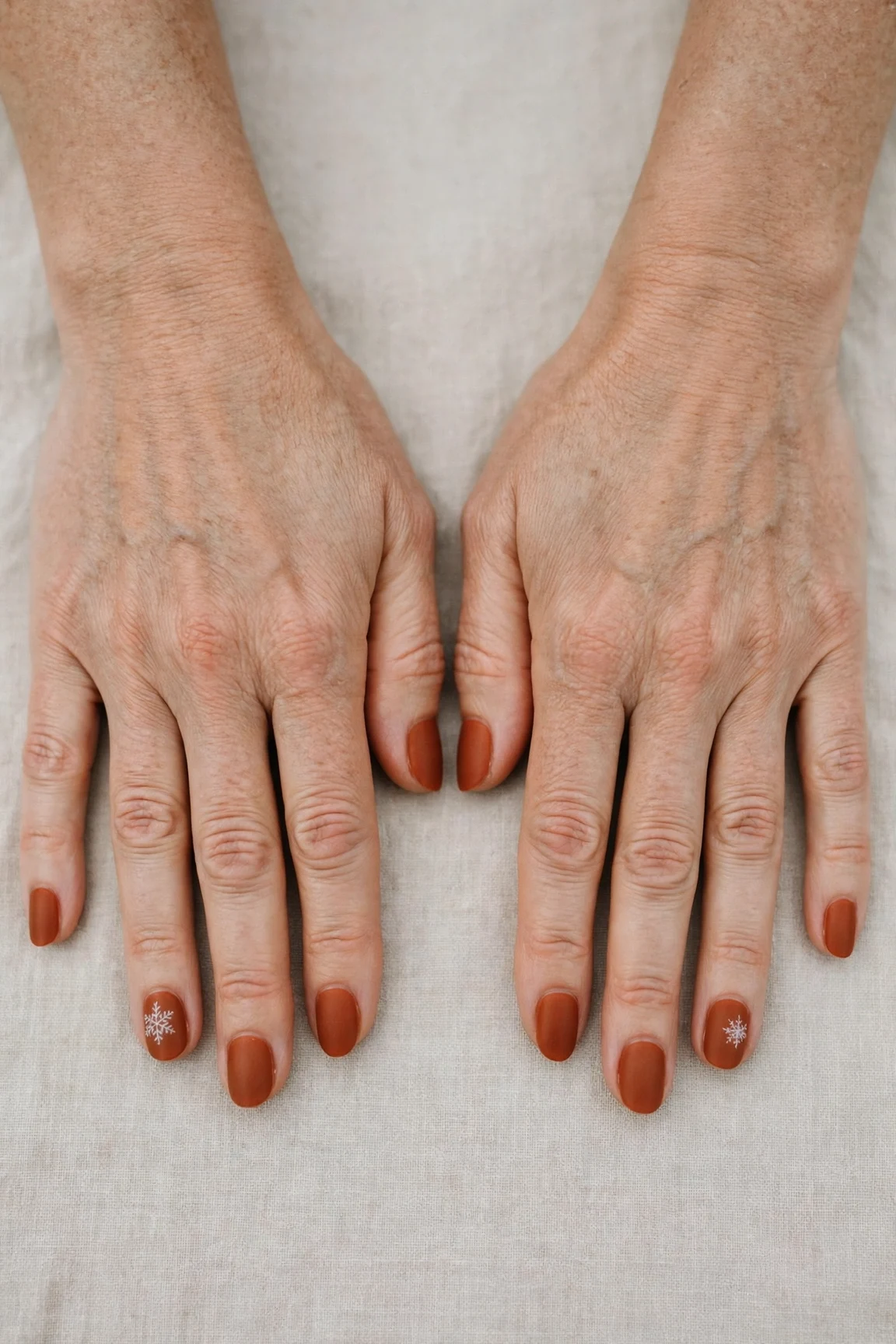 Cinnamon Terracotta Short Nails with a velvet matte finish and a delicate snowflake on the ring finger