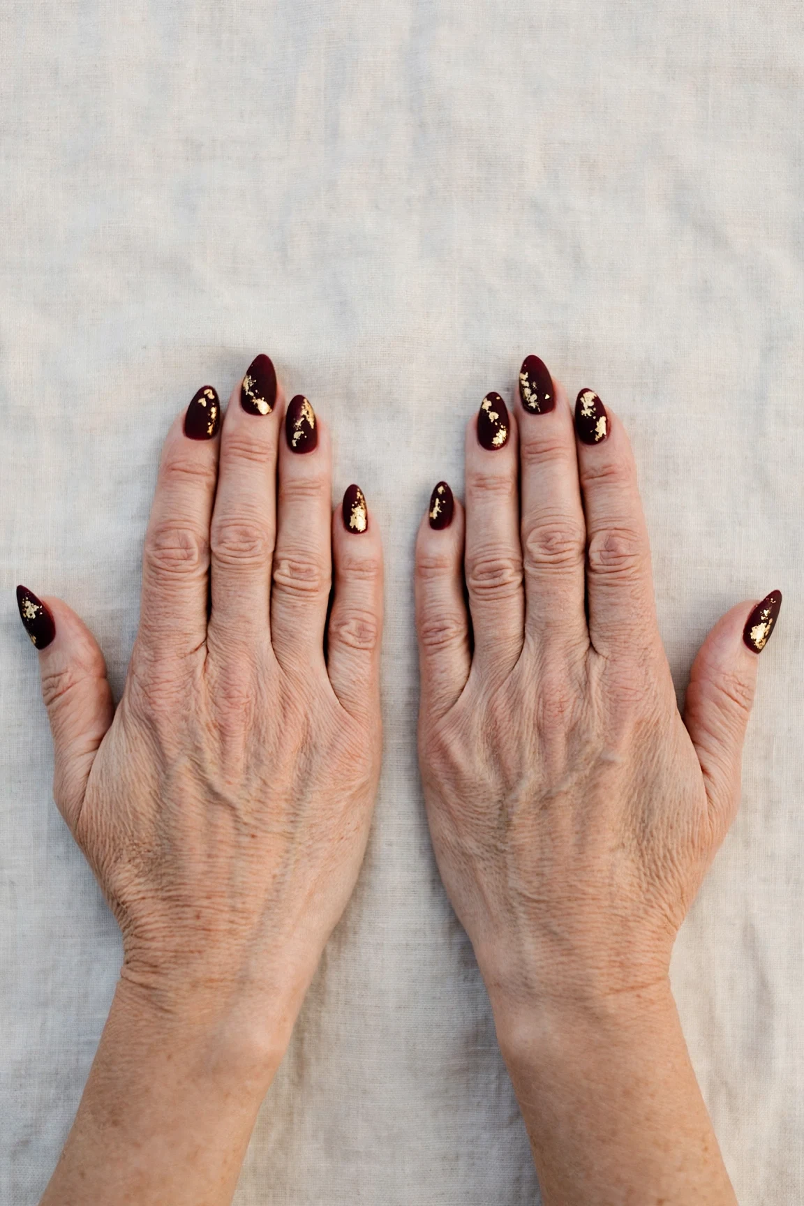 Dark Cherry Velvet Almond Nails with a soft matte finish and gold foil accents