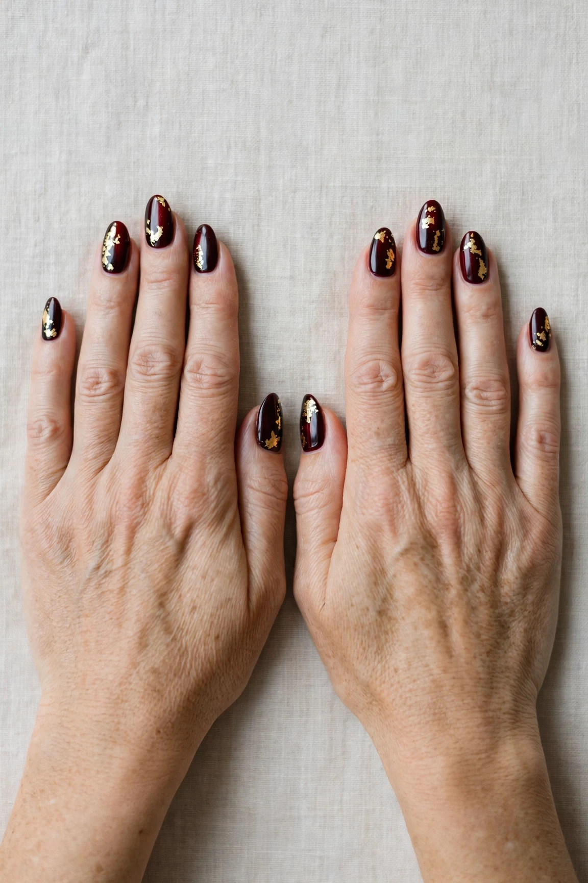 Dark Cherry Velvet Almond Nails with a chrome shine and gold foil accents
