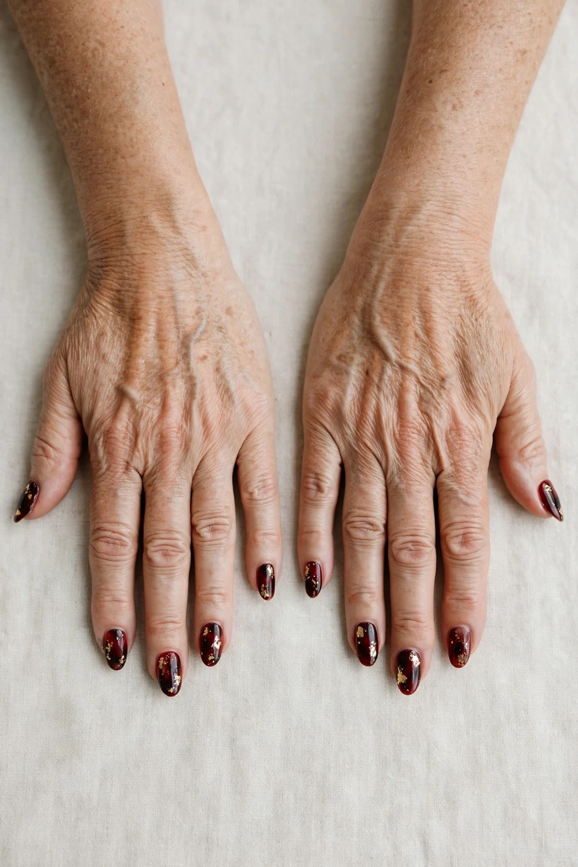 Dark Cherry Velvet Almond Nails with a sheer jelly finish and gold foil accents