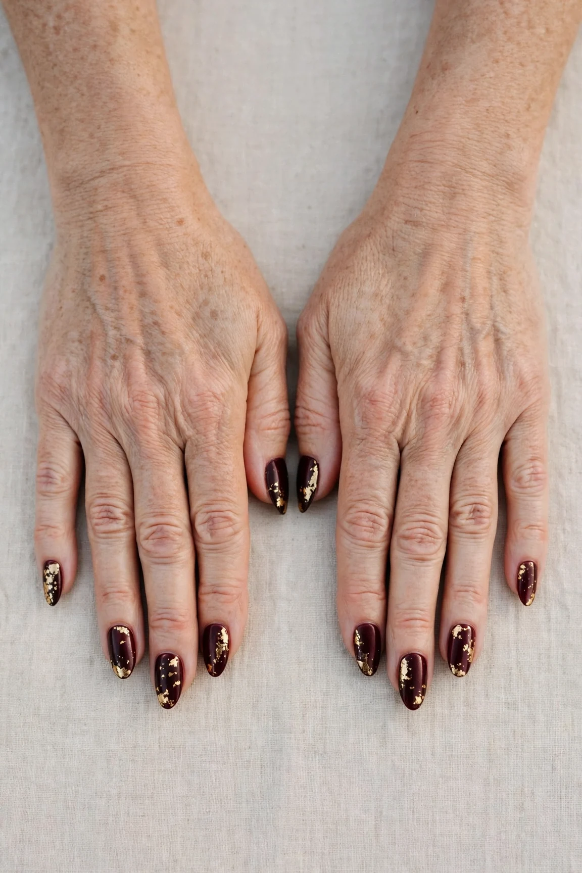 Dark Cherry Velvet Almond Nails with a satin finish and gold foil accents