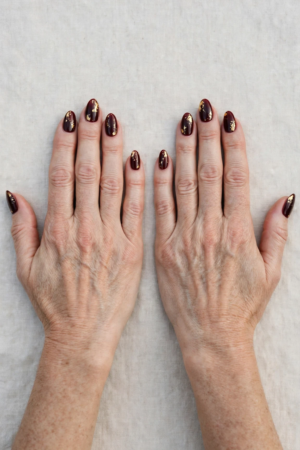 Dark Cherry Velvet Almond Nails with a glassy gel finish and gold foil accents