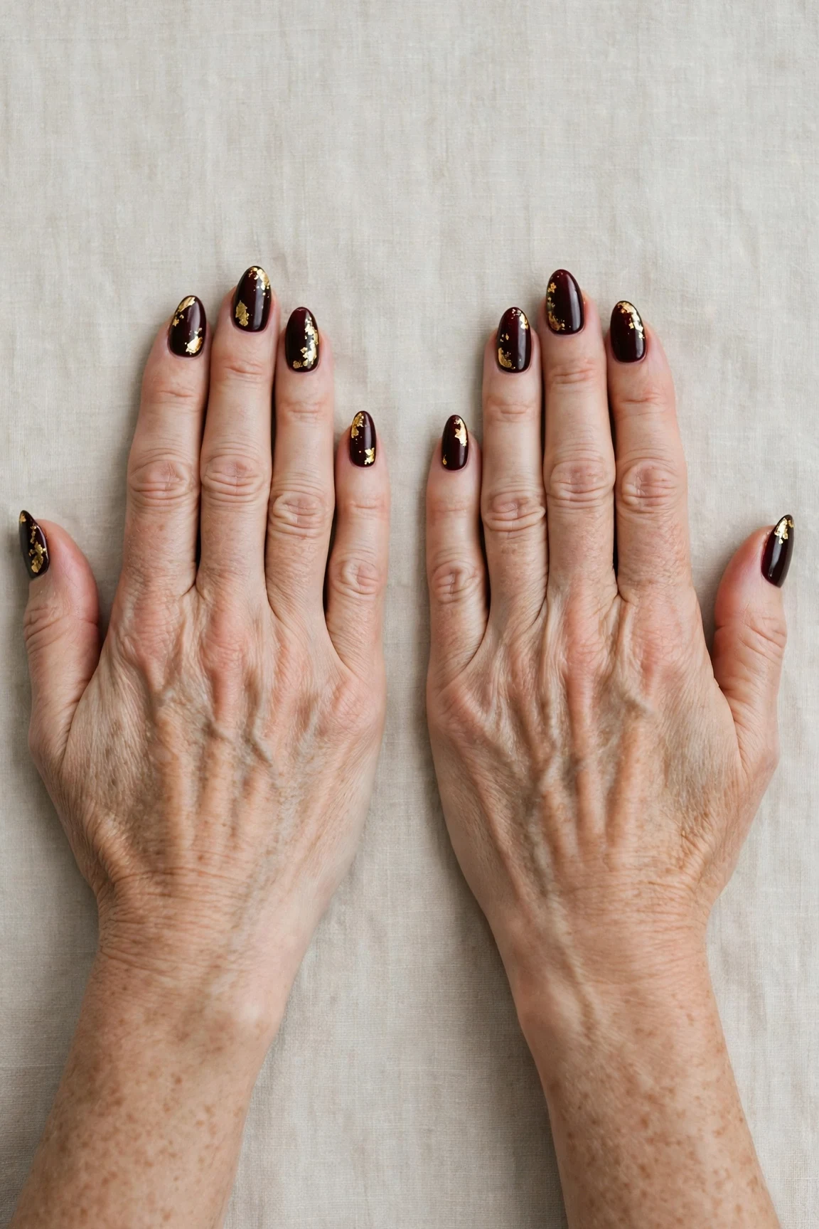Dark Cherry Velvet Almond Nails with a creamy opaque finish and gold foil accents