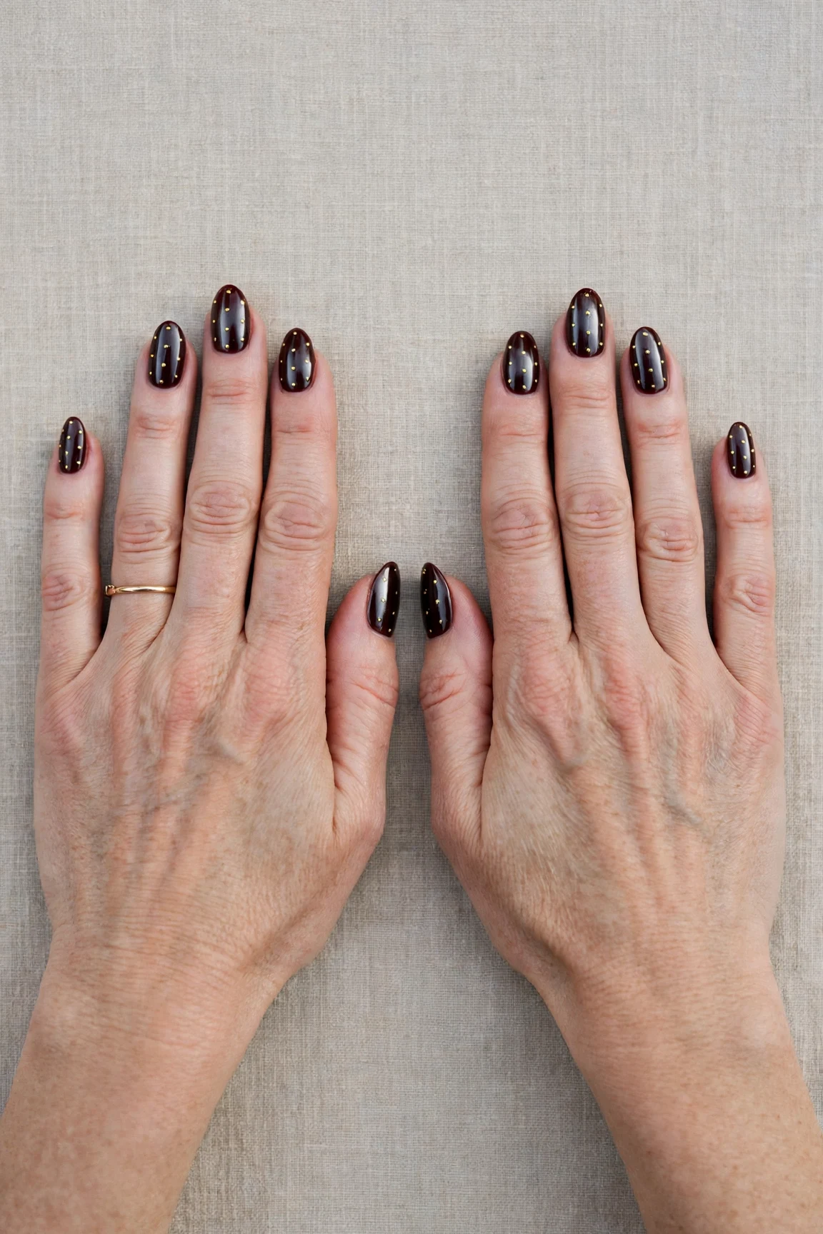 Dark Cherry Velvet Almond Nails with a chrome shine and tiny gold dots