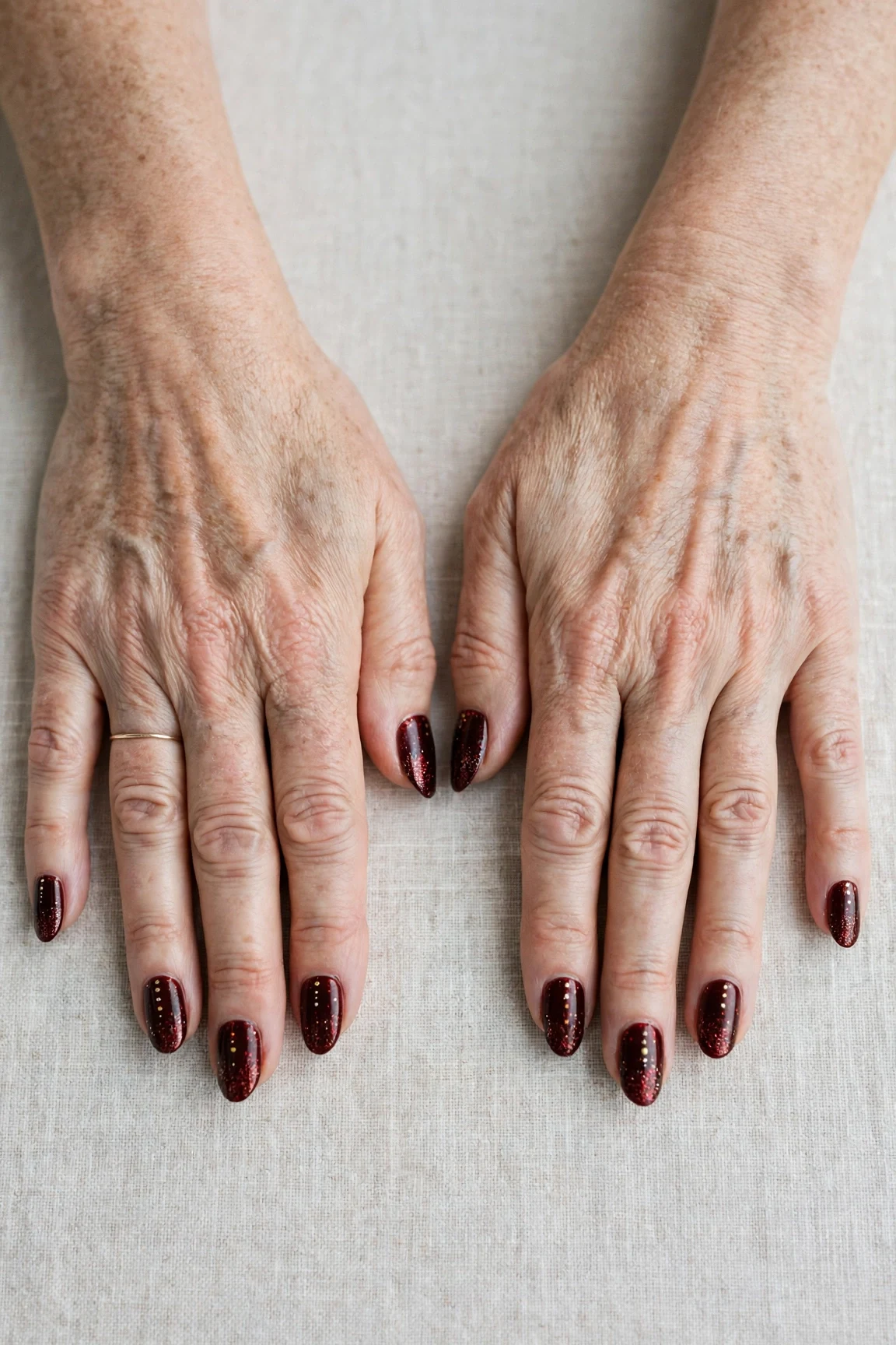 Dark Cherry Velvet Almond Nails with a glitter gradient finish and tiny gold dots