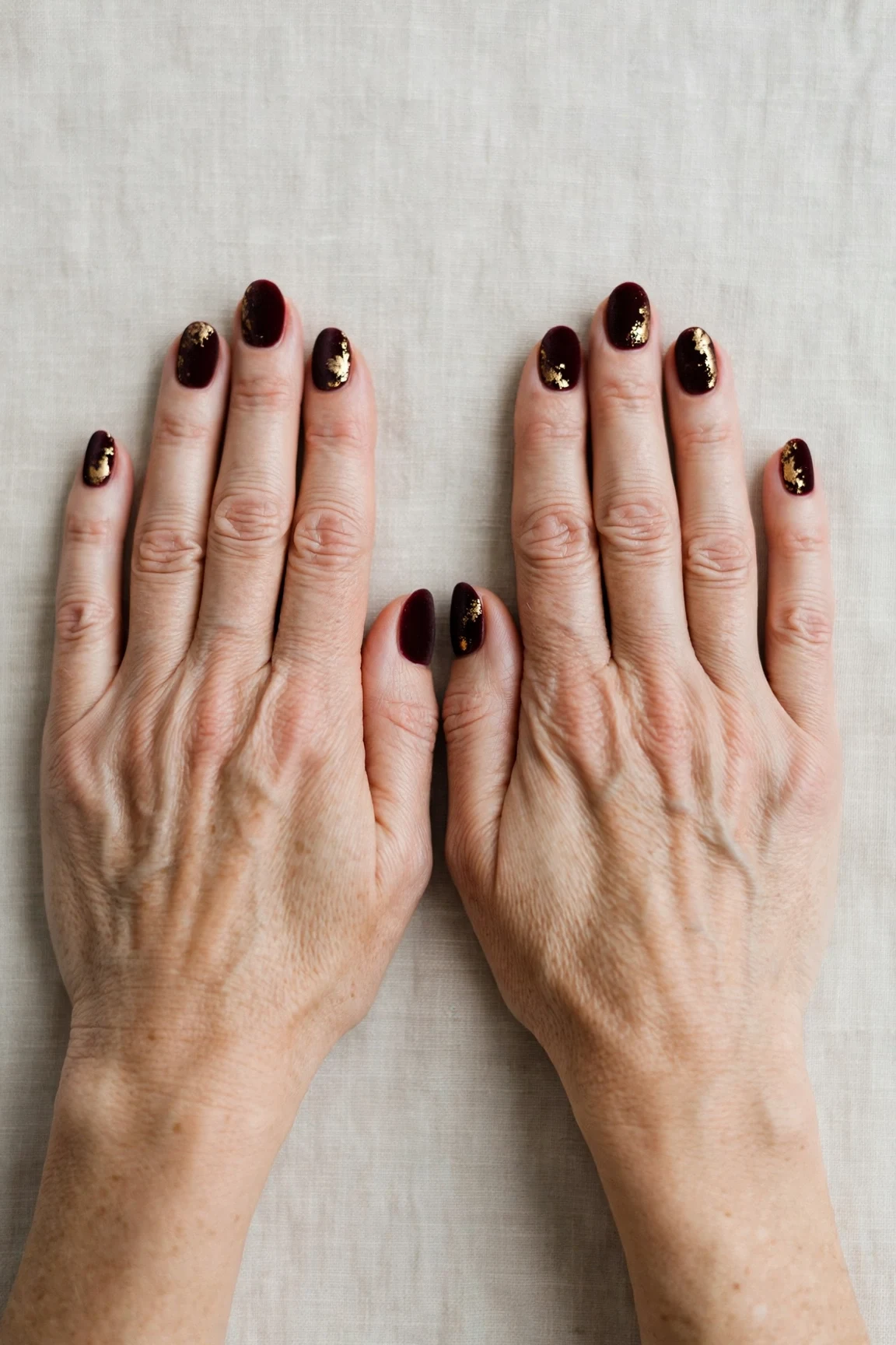 Oval Dark Cherry Velvet Manicure Ideas with a velvet matte finish and gold foil accents