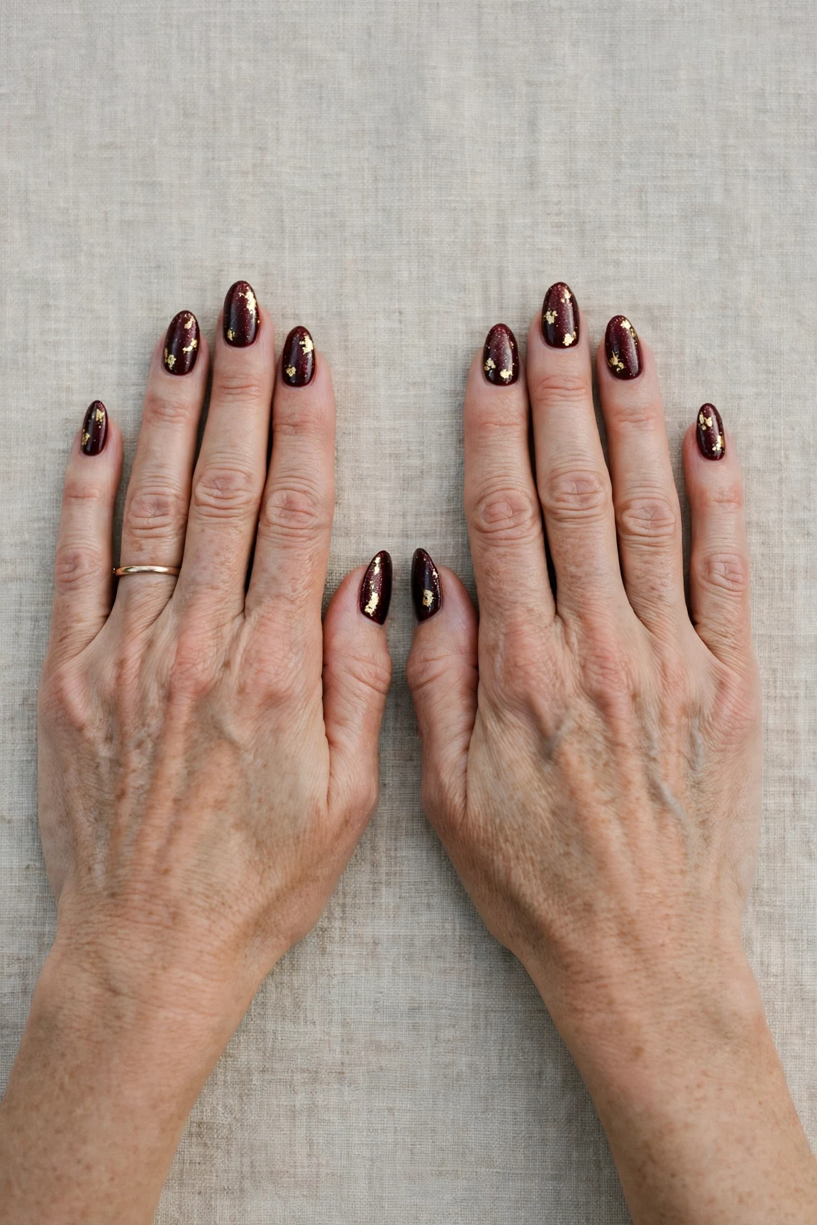 Almond Dark Cherry Velvet Manicure Ideas with a pearl shimmer finish and gold foil accents