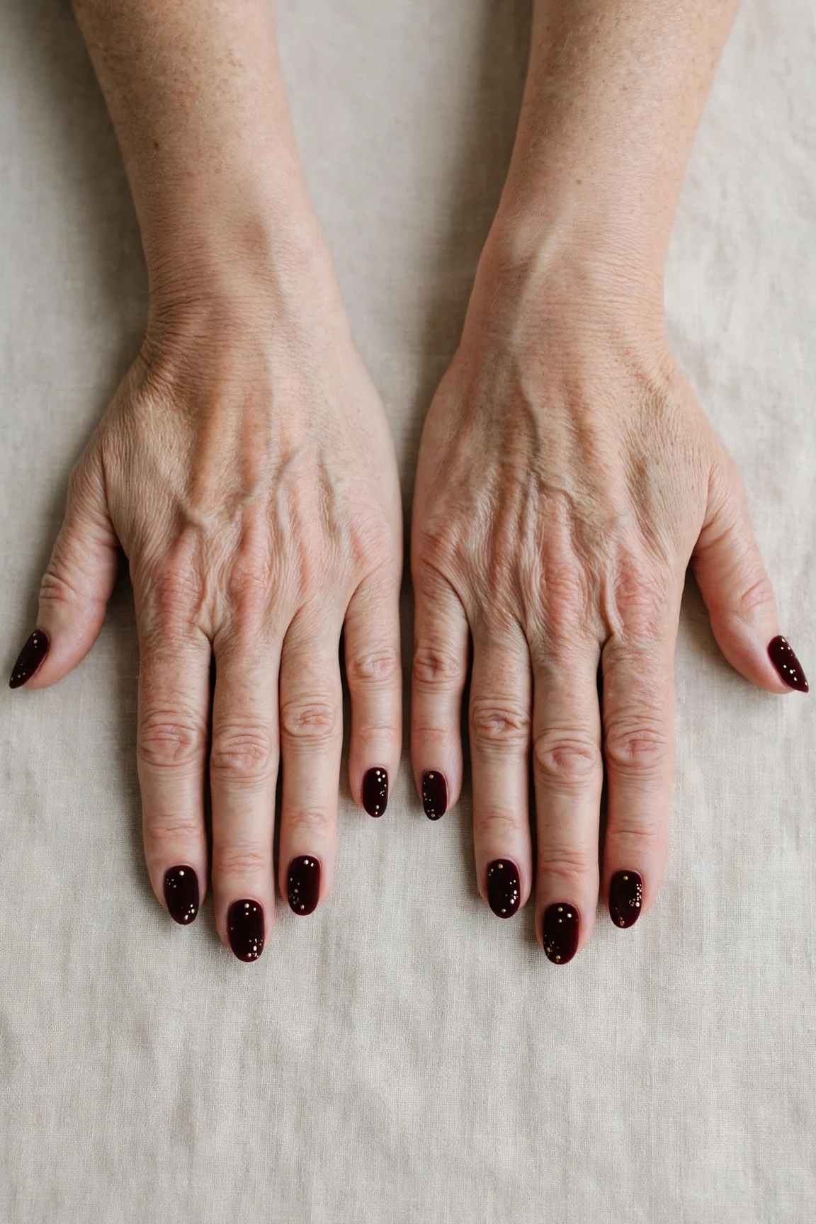 Almond Dark Cherry Velvet Manicure Ideas with a soft matte finish and tiny gold dots