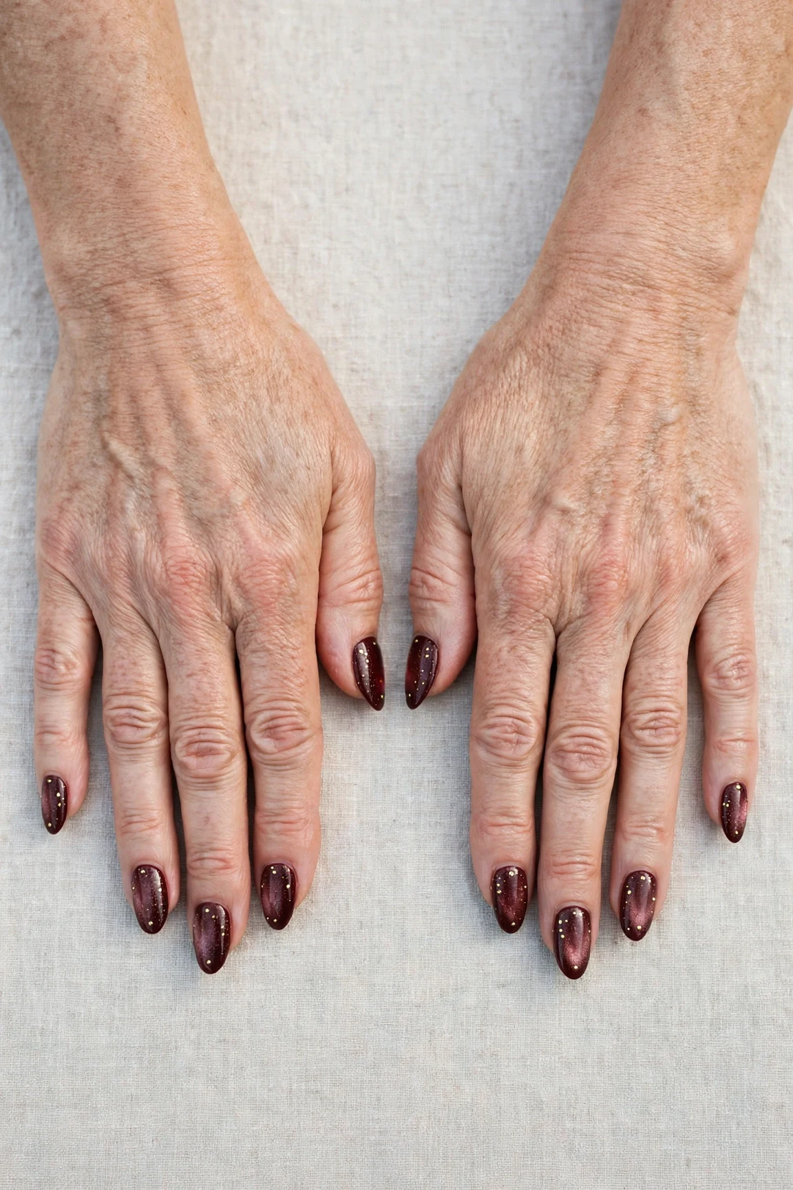 Almond Dark Cherry Velvet Manicure Ideas with a pearl shimmer finish and tiny gold dots