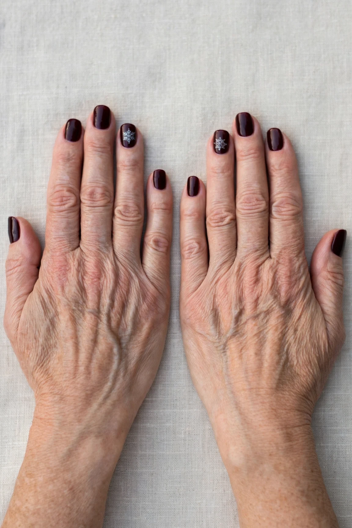 Short Oval Dark Cherry Velvet Manicure Ideas with a high-gloss finish and a delicate snowflake on the ring finger