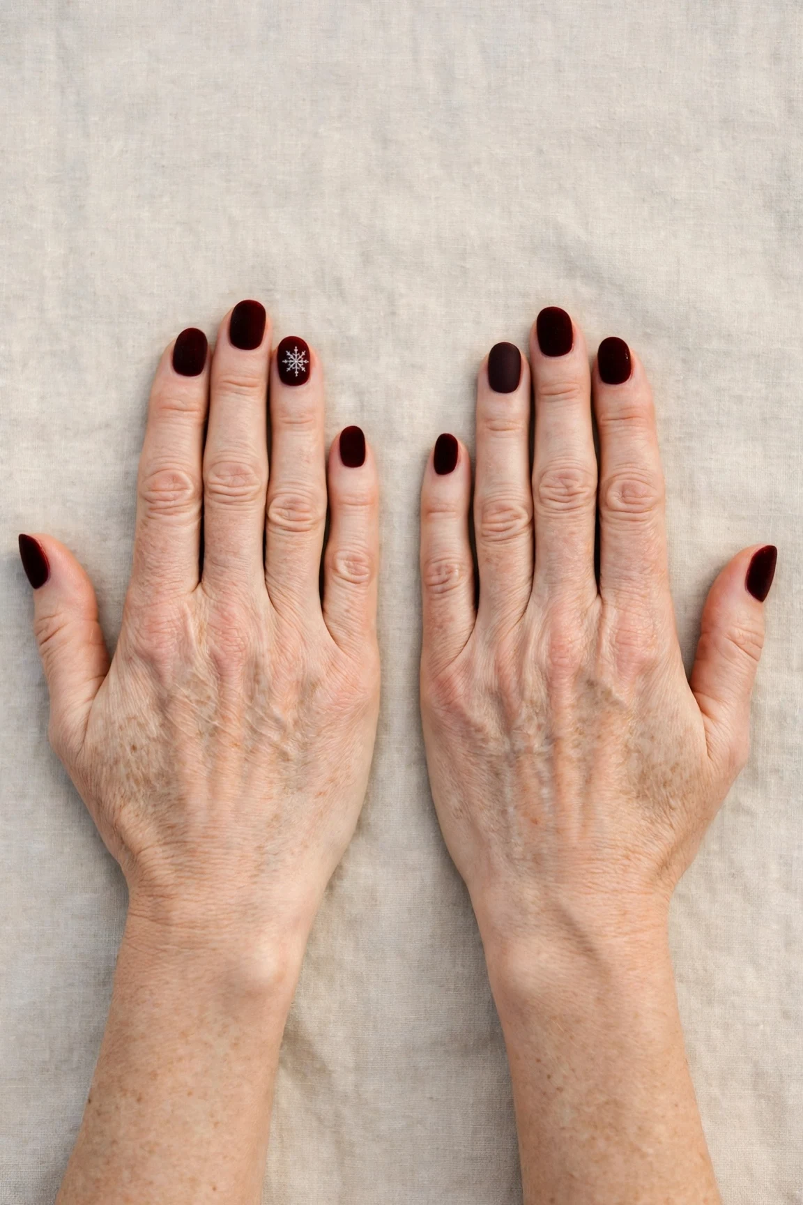 Oval Dark Cherry Velvet Manicure Ideas with a velvet matte finish and a delicate snowflake on the ring finger
