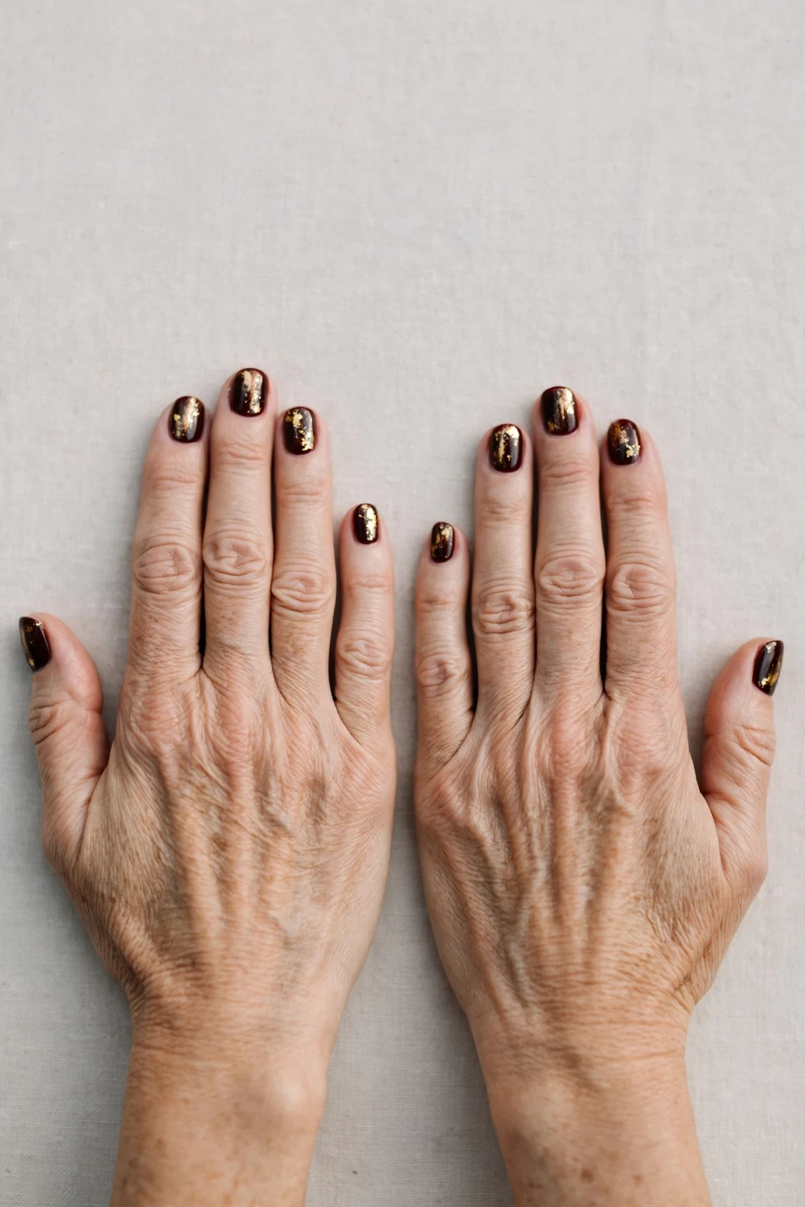 Short Round Dark Cherry Velvet Nails with a deep glossy shine and gold foil accents
