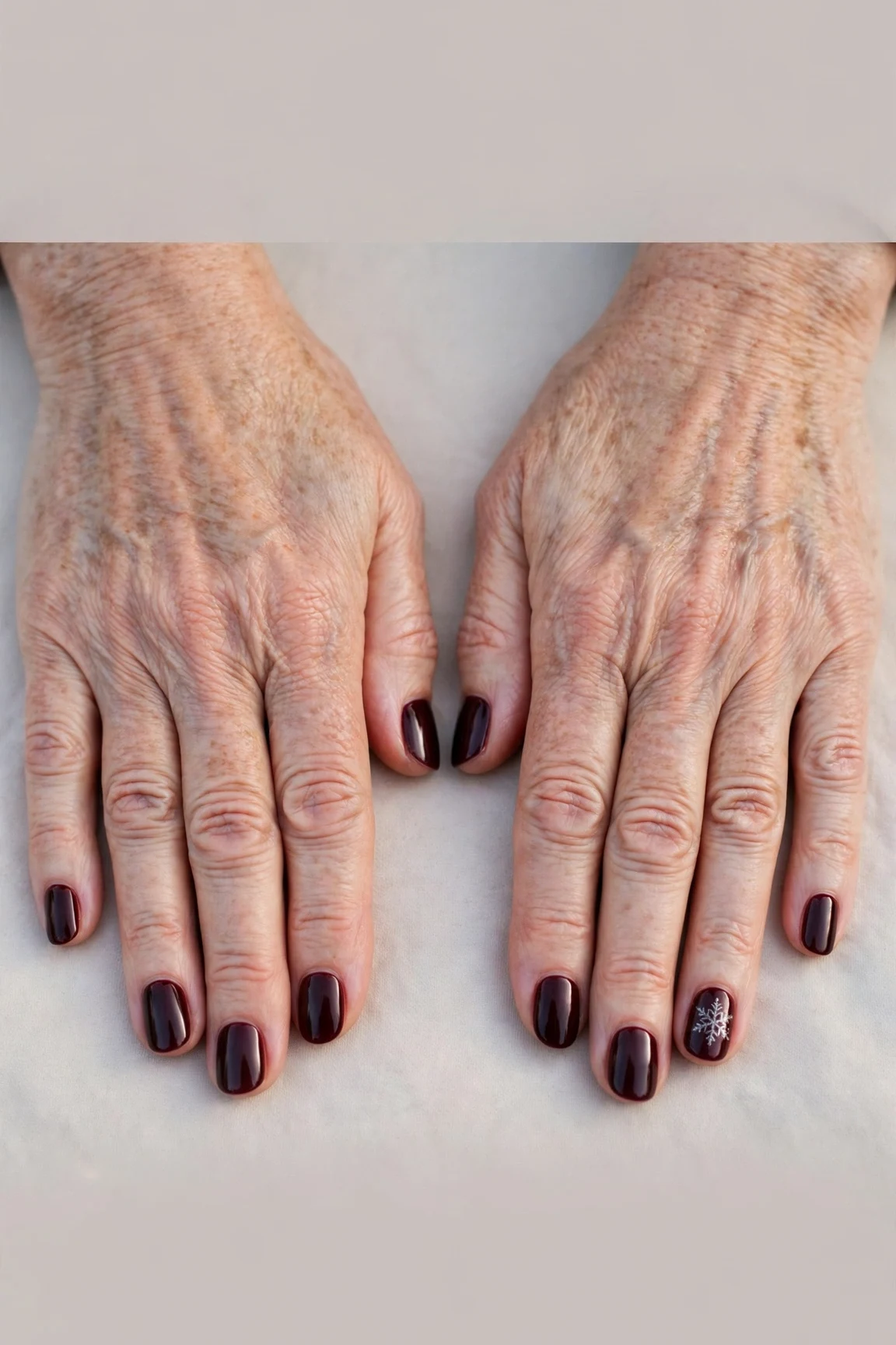 Short Oval Dark Cherry Velvet Nails with a high-gloss finish and a delicate snowflake on the ring finger