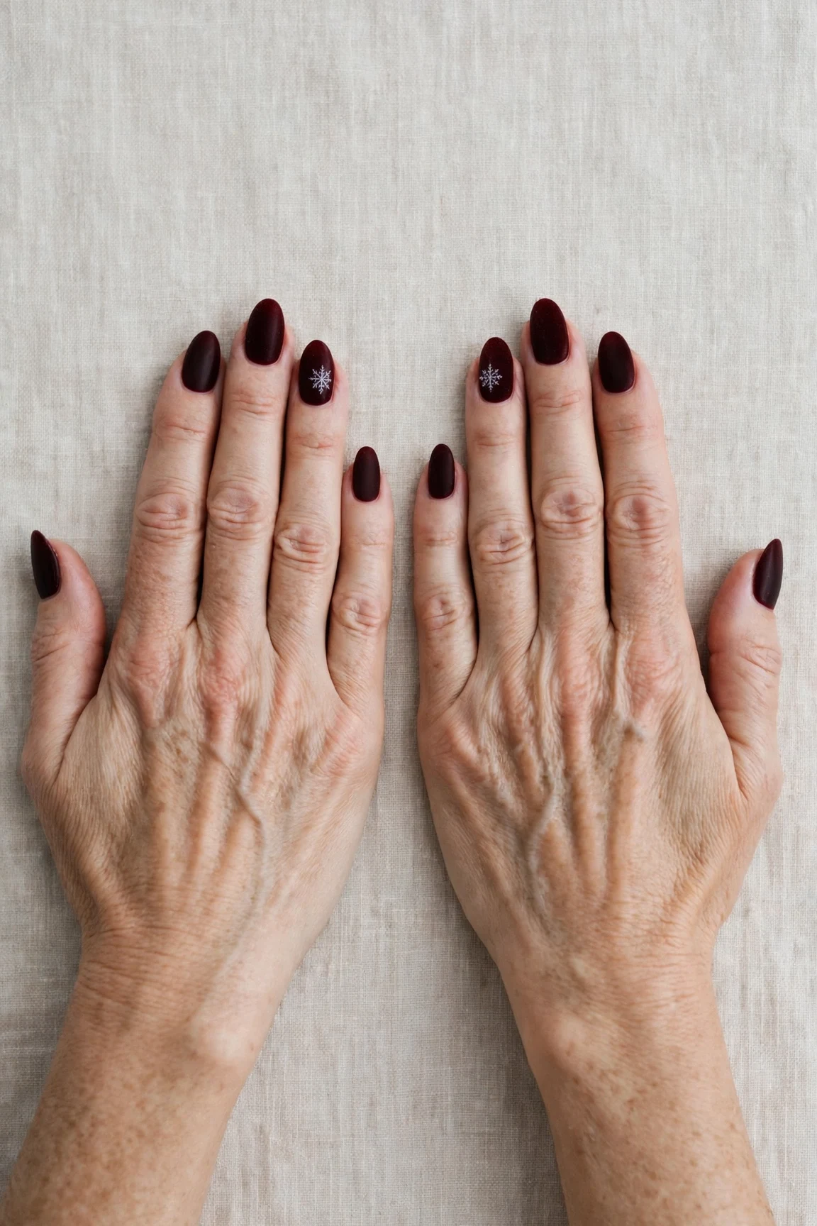 Almond Dark Cherry Velvet Nails with a soft matte finish and a delicate snowflake on the ring finger