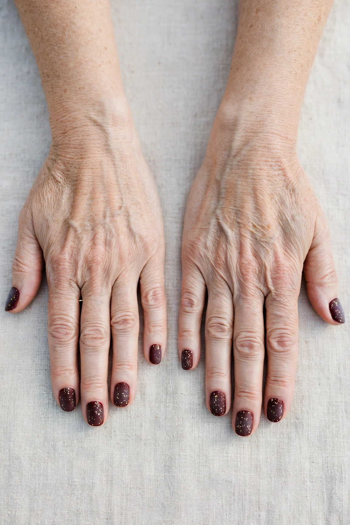 Dark Cherry Velvet Short Nails with a frosted shimmer finish and tiny gold dots