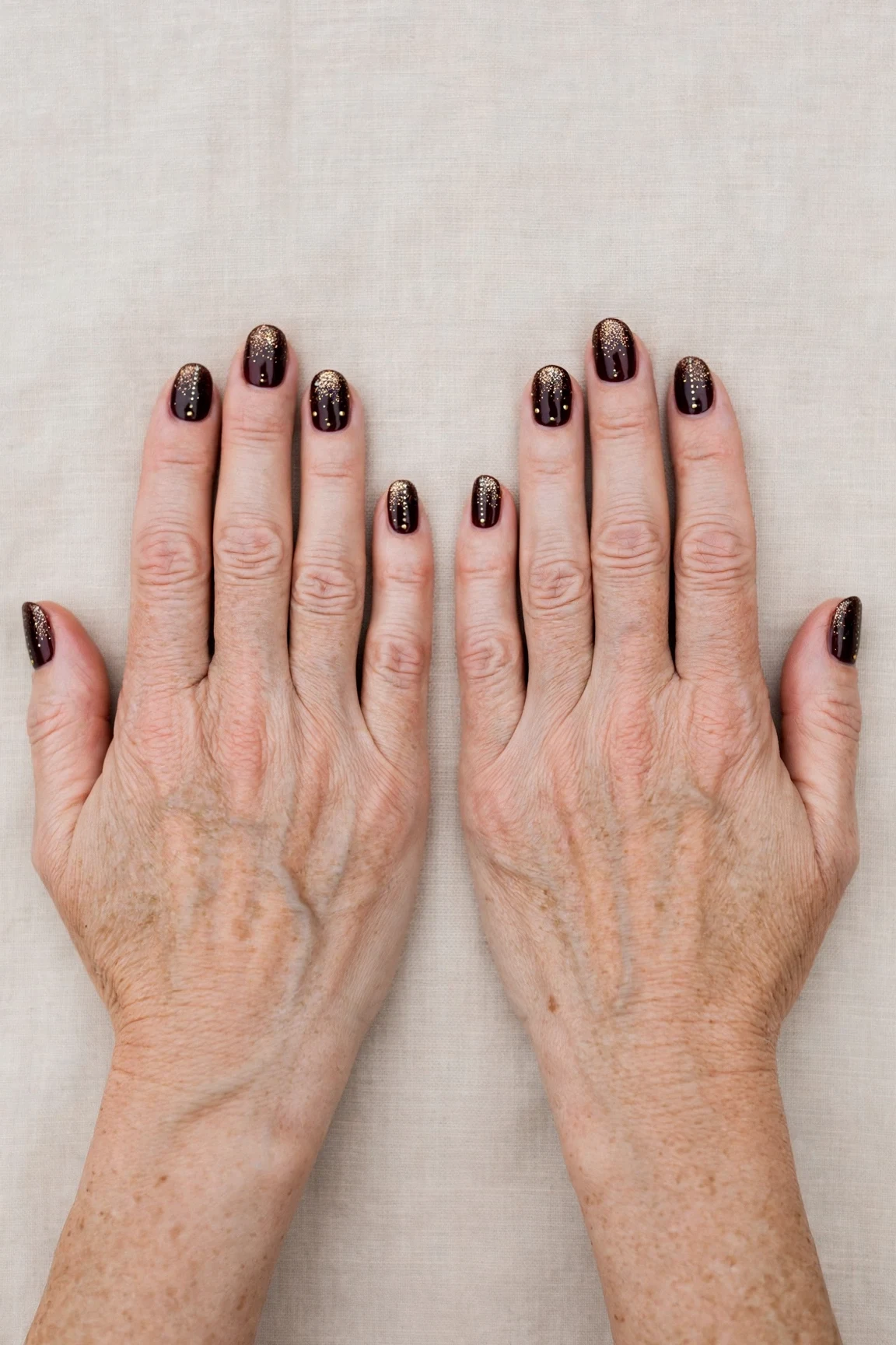 Dark Cherry Velvet Short Nails with a glitter gradient finish and tiny gold dots